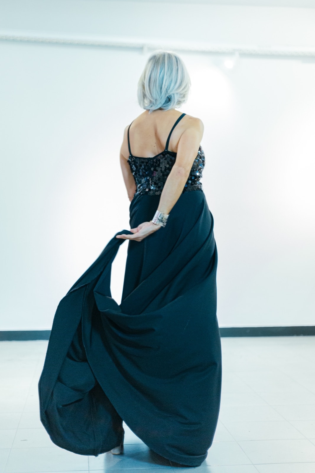 Black sequins and crepe dress, vista de espalda sobre modelo, con tiras finas y la falda en movimiento.