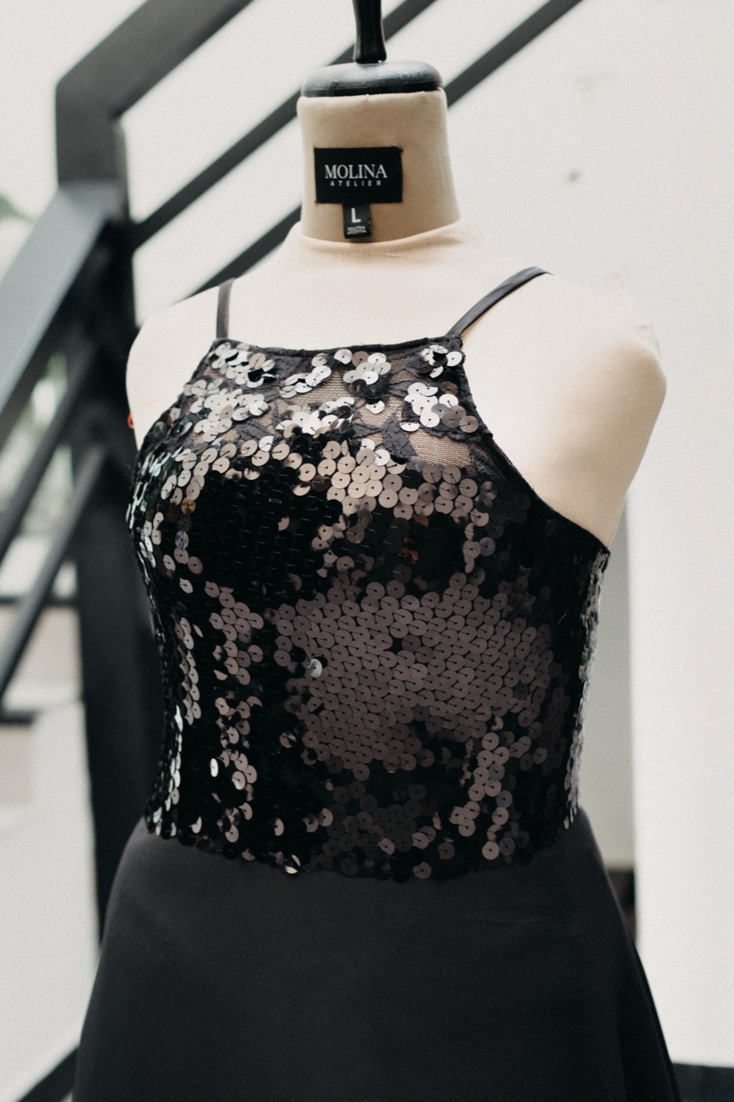 Detalle del bustier de paillette y lentejuelas circulares del Black sequins and crepe dress, primer plano sobre maniquí.