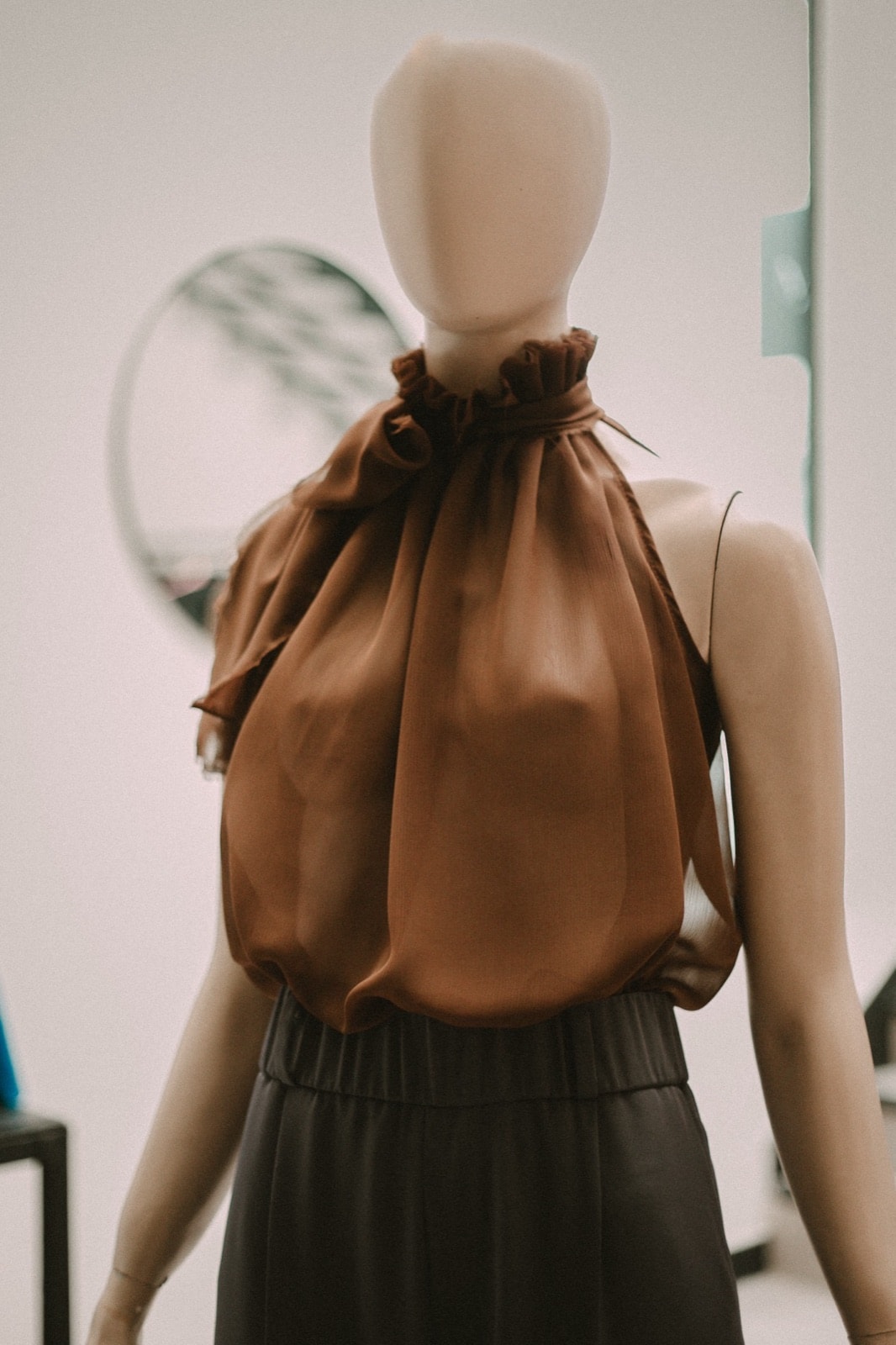 Blusa de gasa bambula chocolate sobre maniquí, vista frontal cercana que muestra el volumen del cuerpo y el lazo lateral.