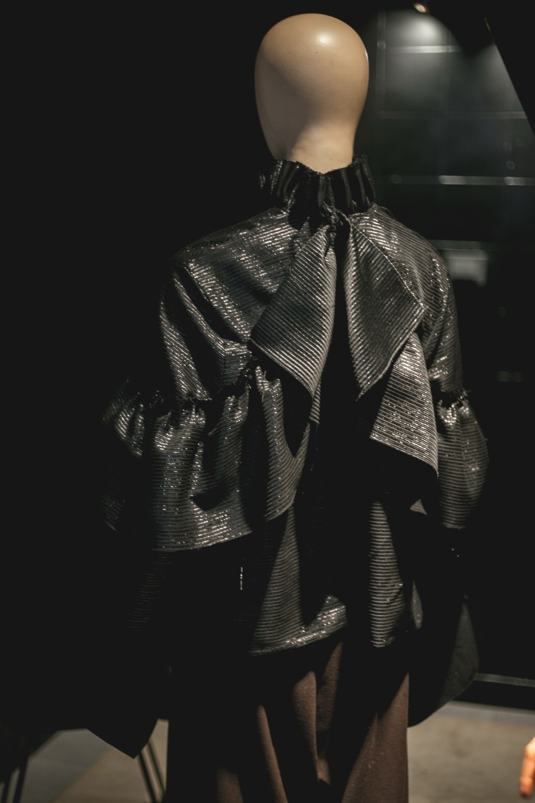 Blusa Olé! Negra Texturizada sobre maniquí, vista de espalda con los volados cruzados en la zona alta.