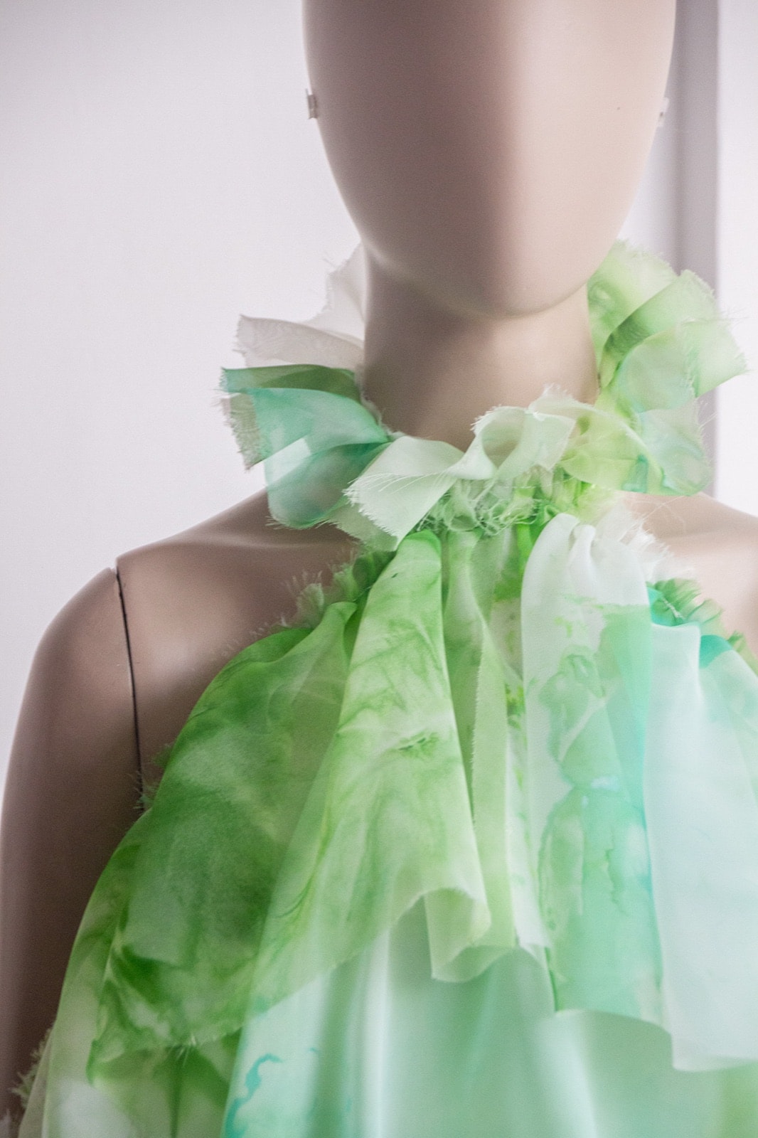 Detalle del cuello alto fruncido de la Blusa Olé! Verde sobre maniquí, mostrando los bordes deshilachados de la gasa.