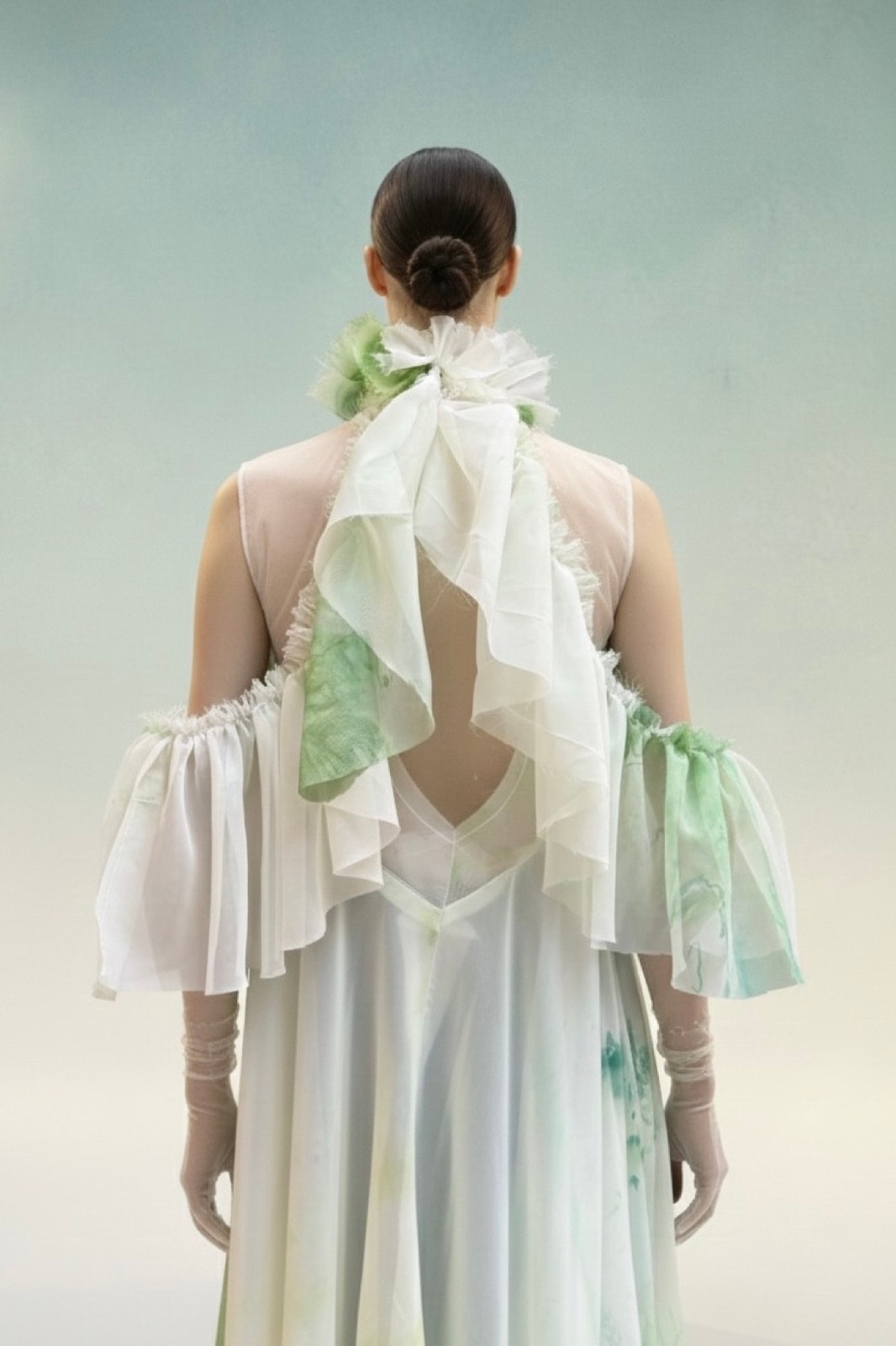 Blusa Olé! Verde sobre modelo, vista de espalda con el lazo del cuello alto y las mangas con volados abullonados.