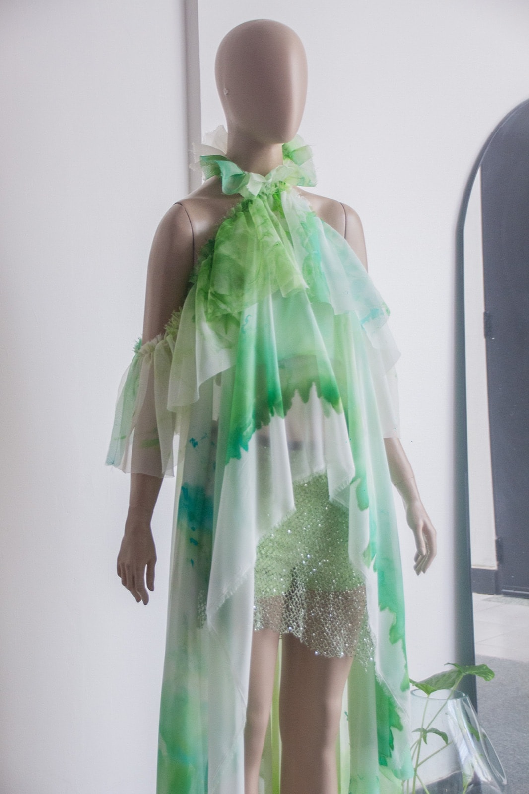 Blusa Olé! Verde de Atelier Molina sobre maniquí, vista frontal completa en un ambiente interior con planta de fondo.