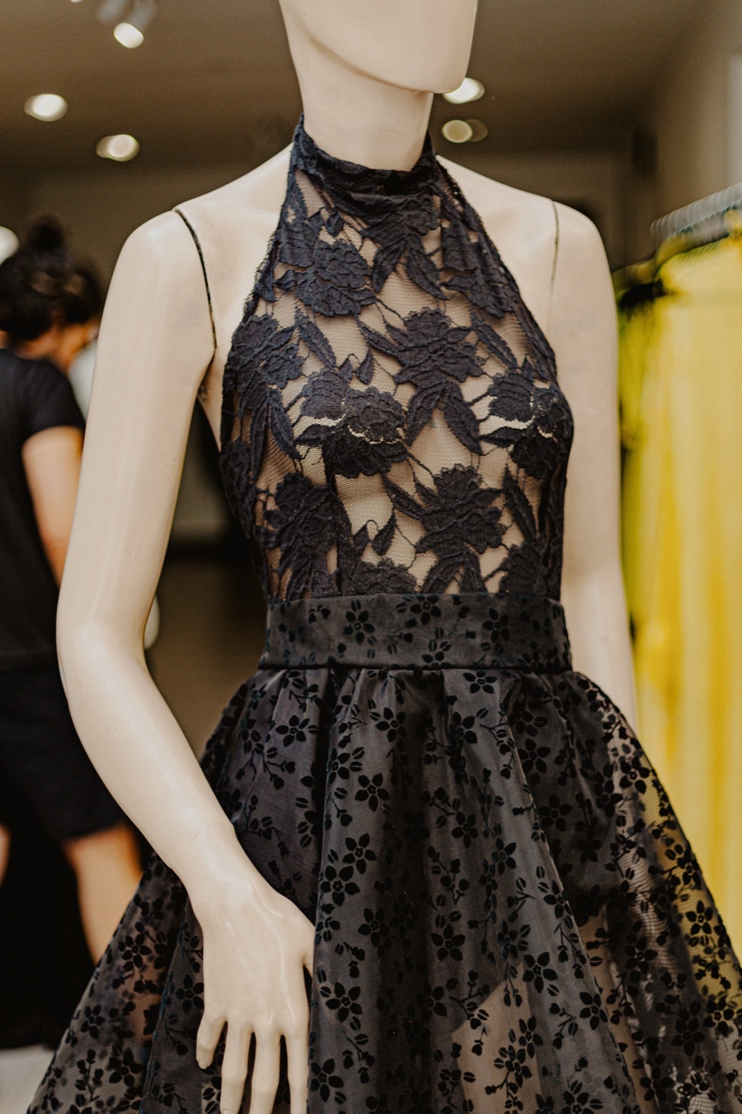 Body de encaje negro con motivo floral, vista frontal sobre maniquí en el local, con falda amplia a juego.