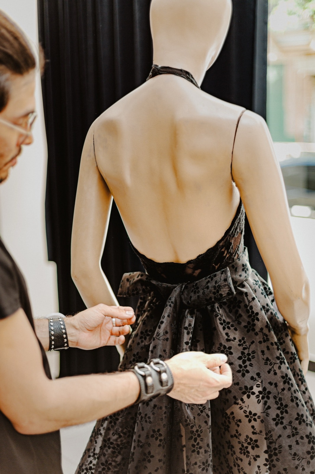 Body de encaje negro, vista de espalda descubierta sobre maniquí, con el lazo de la falda siendo ajustado.