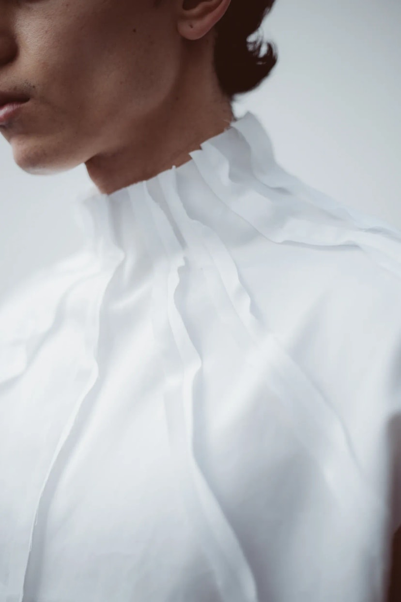 Camisa Radial blanca de cuello alto tableado y bordes al descubierto, de la línea PLIEGO de Atelier Molina, distinguida con el Sello de Buen Diseño Argentino 2026. Buenos Aires.
