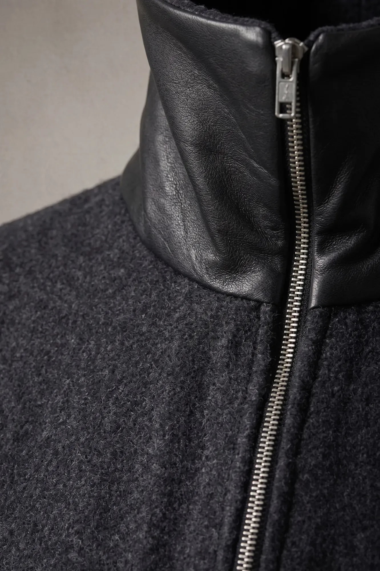 Detalle del cuello alto en cuero napa negro y el cierre metálico de la chaqueta de lana prensada de Atelier Molina.