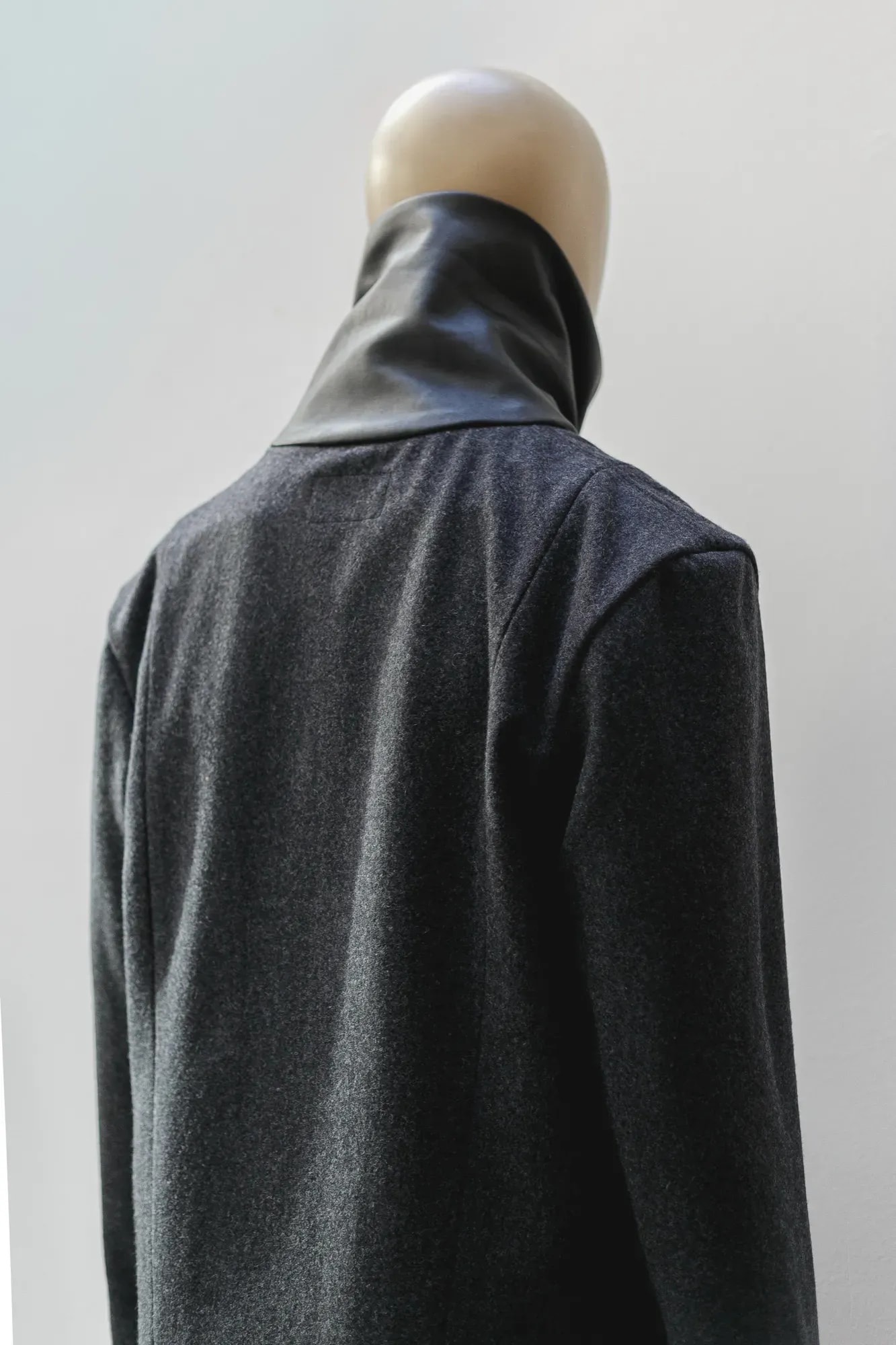 Chaqueta de lana prensada gris con cuello de napa negra de Atelier Molina, plano de producto sobre fondo gris liso.