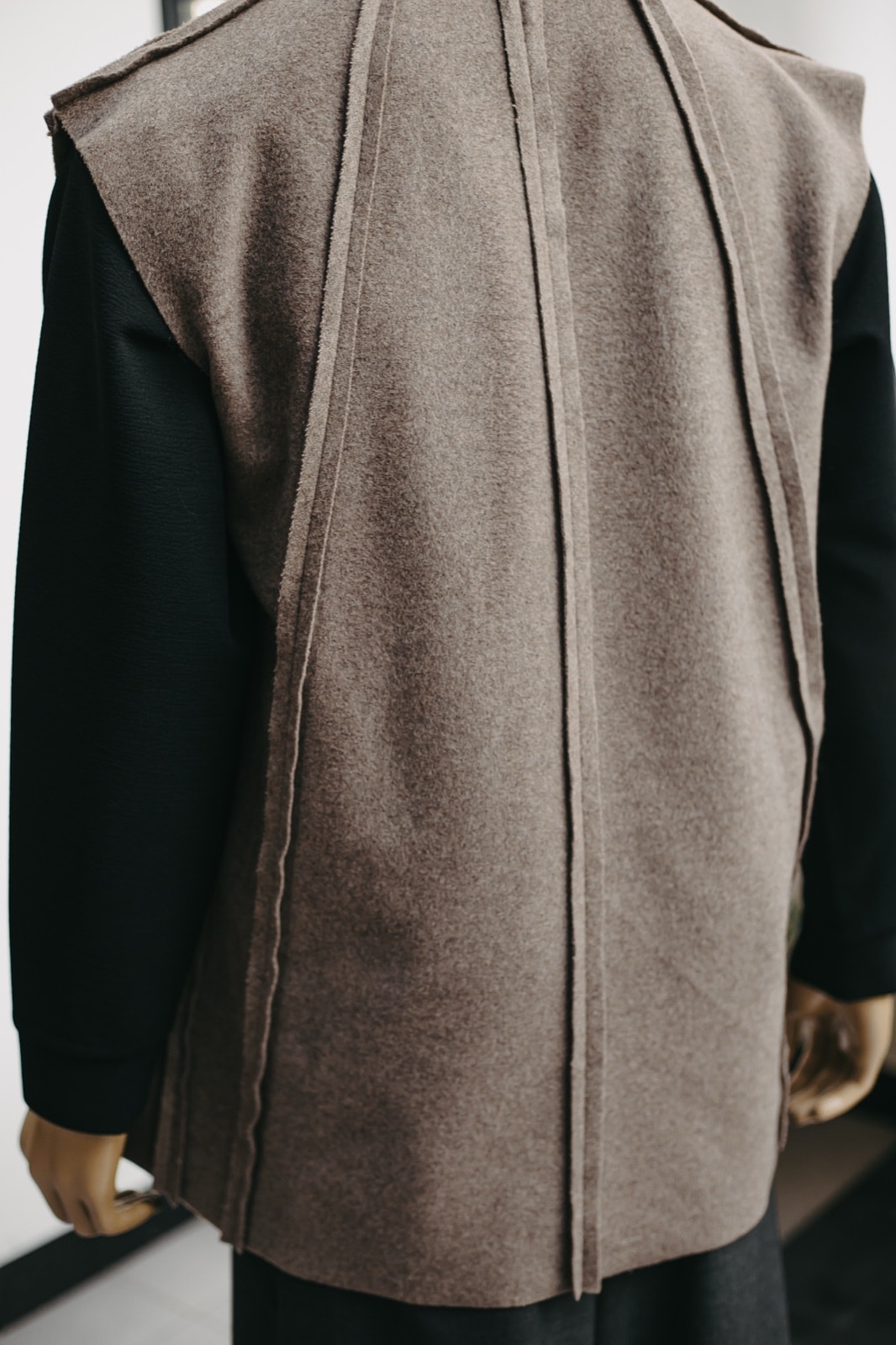 Espalda del chaleco de cashmere sobre maniquí, con las costuras expuestas corriendo verticales desde el cuello hasta el ruedo.