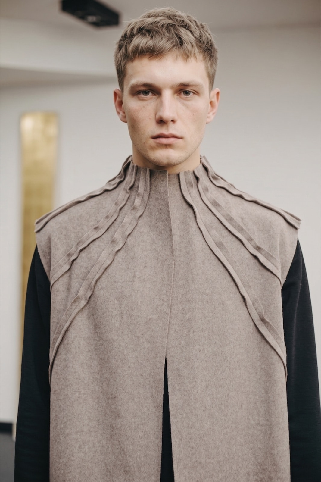 Chaleco de cashmere gris topo sobre modelo, vista frontal cerrada que resalta el cuello alto y la abertura central.