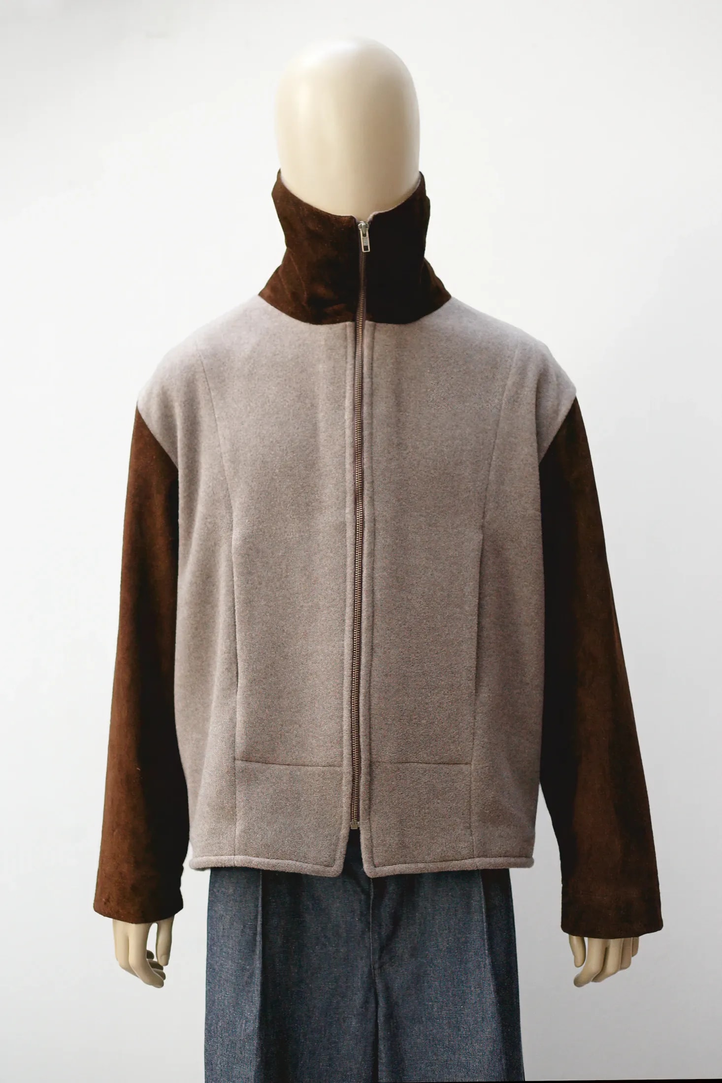 Chaqueta de cashmere gris topo con mangas de cuero de oveja marrón, vista frontal sobre maniquí