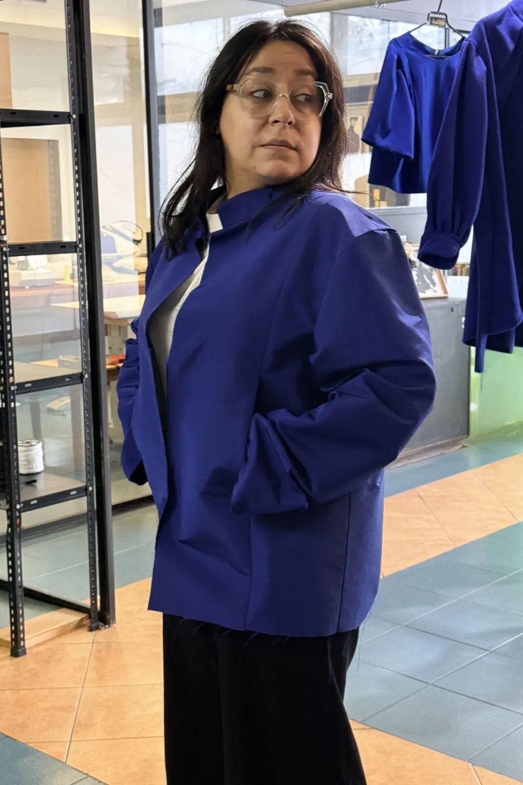Chaqueta de gros de seda azul Klein sobre pantalón negro, vista de perfil que muestra la caída de la manga y el largo hasta la cadera.