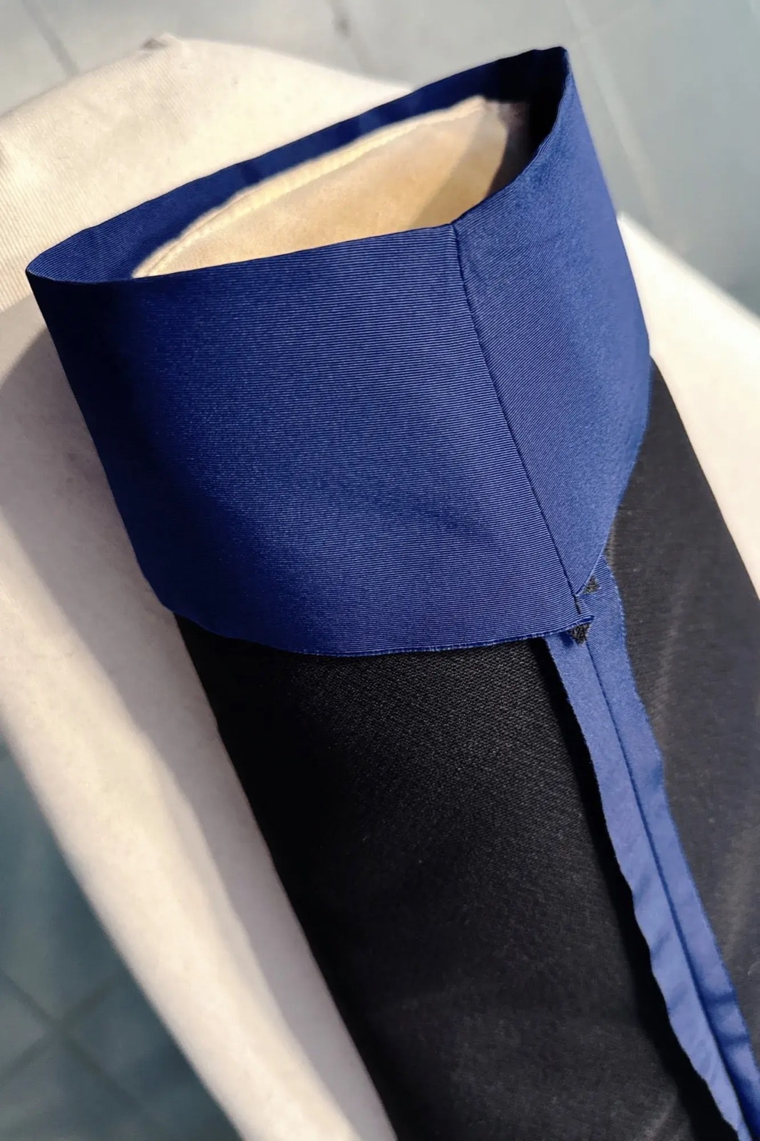 Detalle del cuello alto de la chaqueta azul Klein doblado hacia afuera, que muestra el forro interior color crudo.