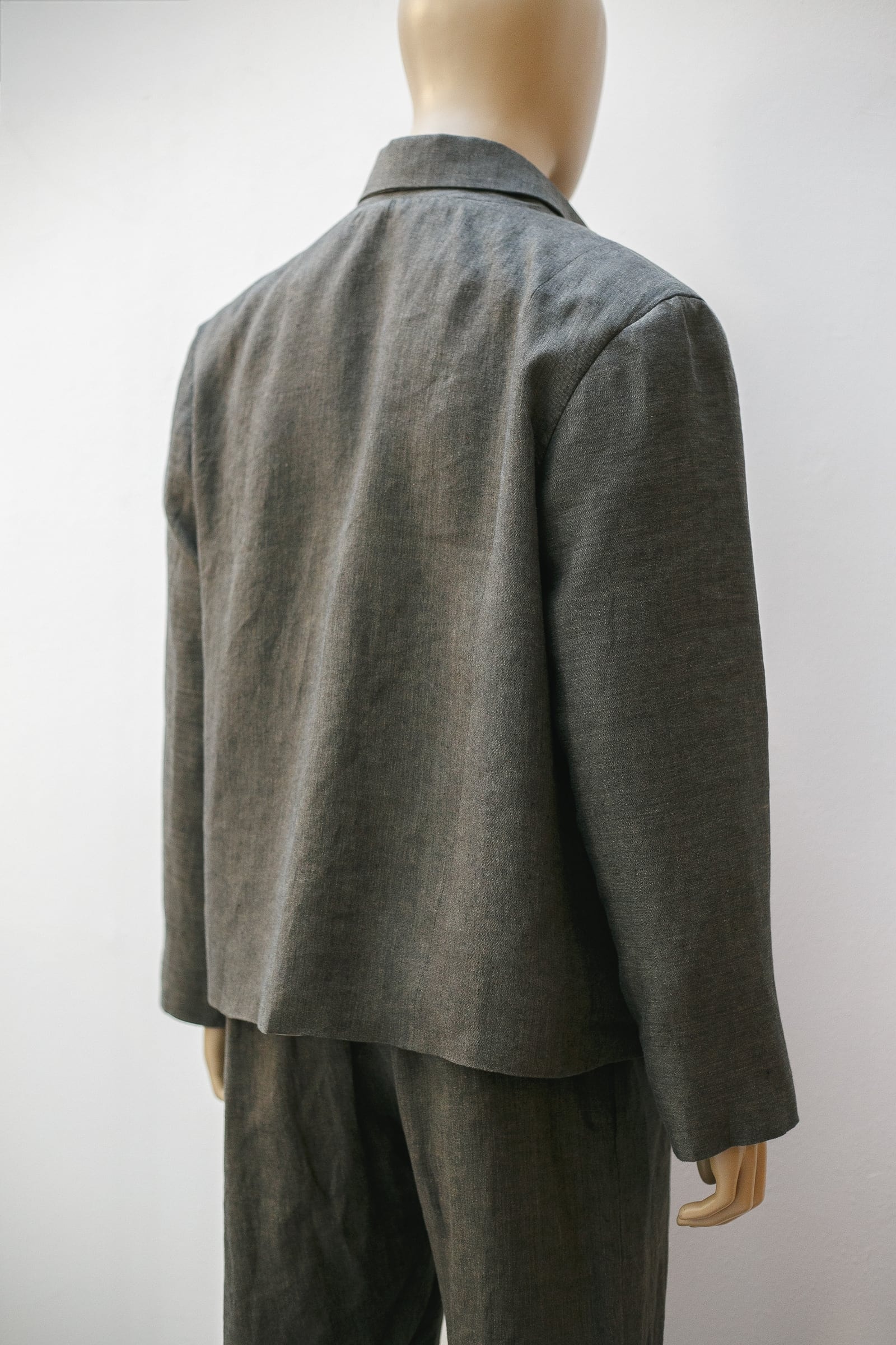 Espalda de la chaqueta de lino italiano verde seco sobre maniquí, mostrando el corte boxy y la caída recta del largo a la cadera.