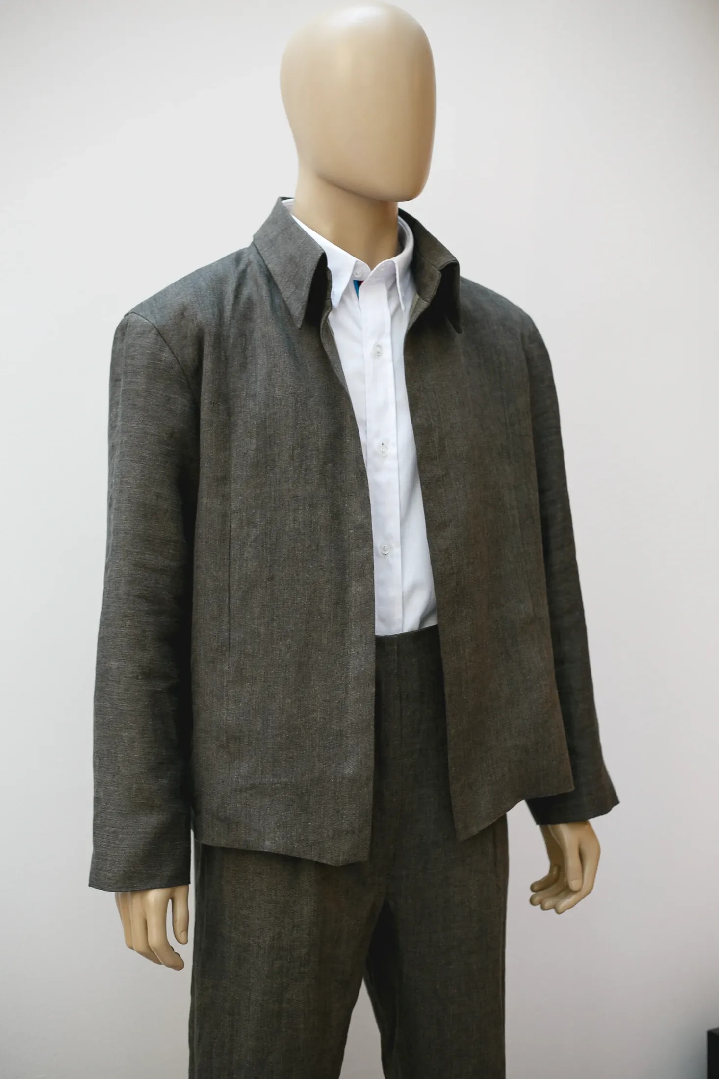 Chaqueta de lino italiano verde seco sobre maniquí, vista de tres cuartos con el cierre abierto y el pantalón a juego.