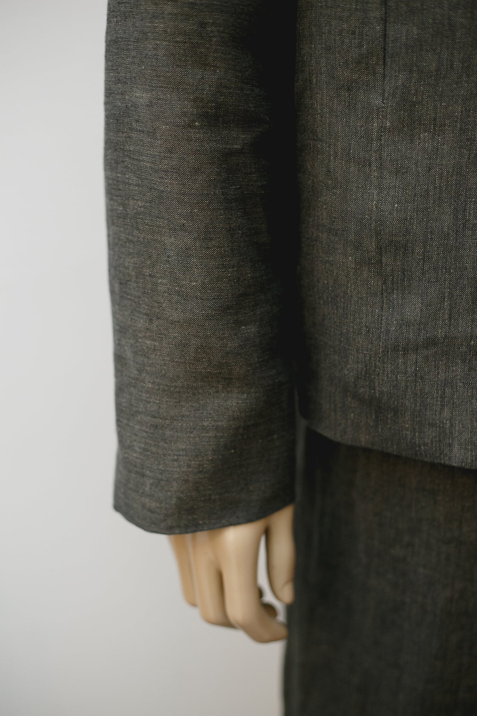 Detalle del ruedo y el puño de la chaqueta de lino italiano verde seco, con la textura irregular propia de la fibra natural.