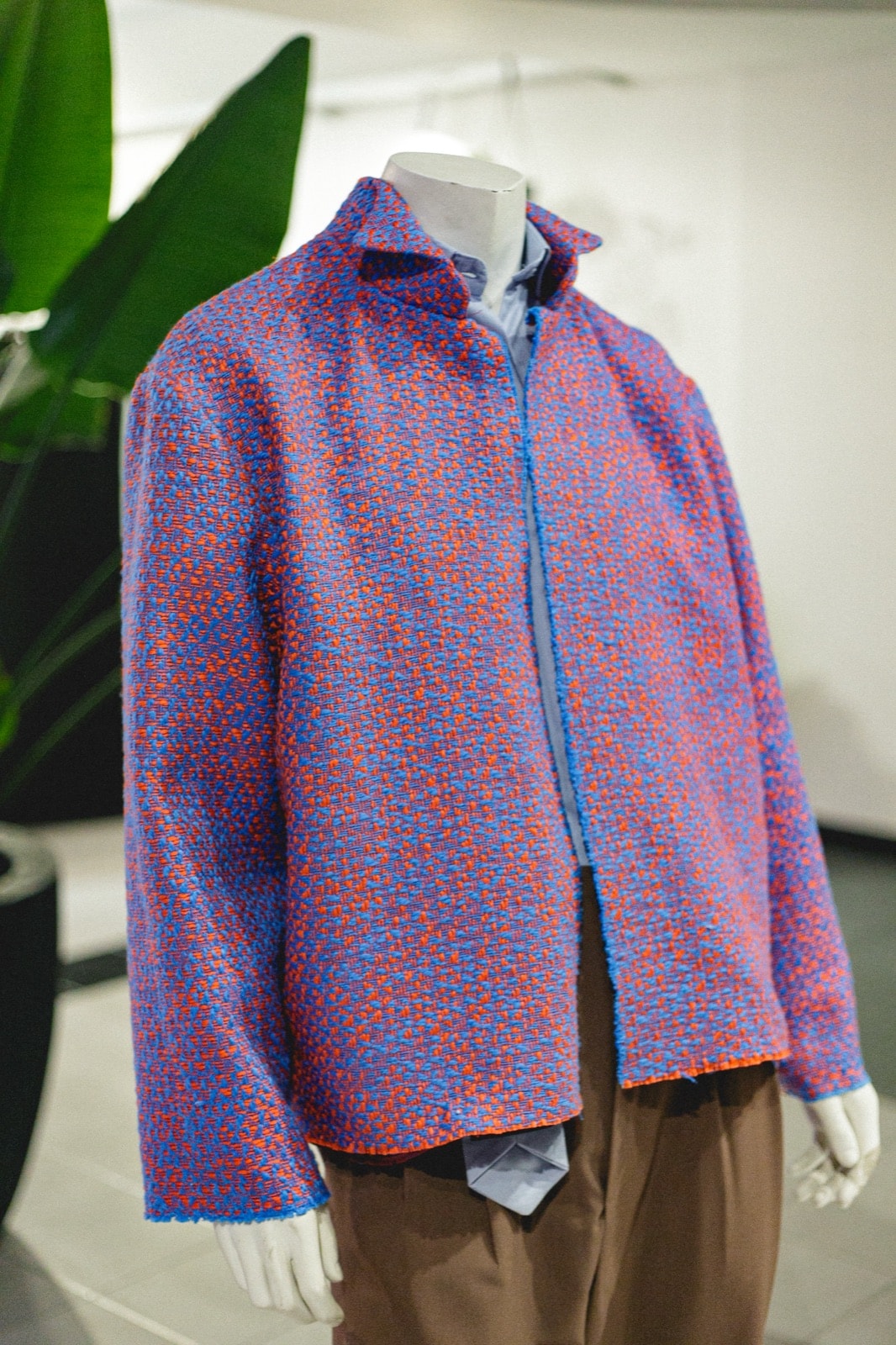 Detalle del tejido de la chaqueta de tweed de algodón azul y naranja, con el cuello levantado, en el atelier