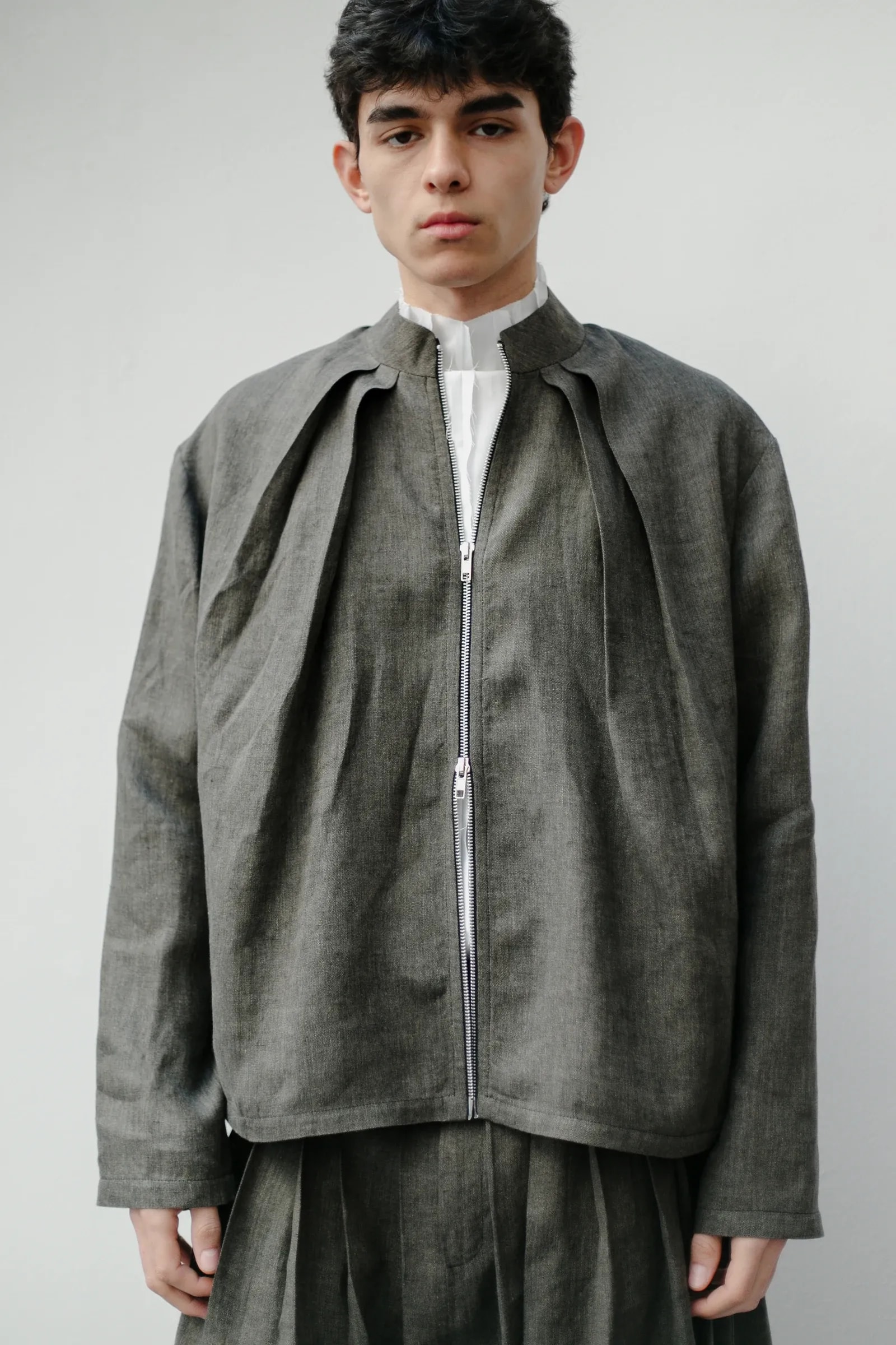 Chaqueta Molina de lino italiano verde alga vista de frente, con los pliegues abiertos desde el hombro y el cierre de doble carro al centro. Atelier Molina, Buenos Aires