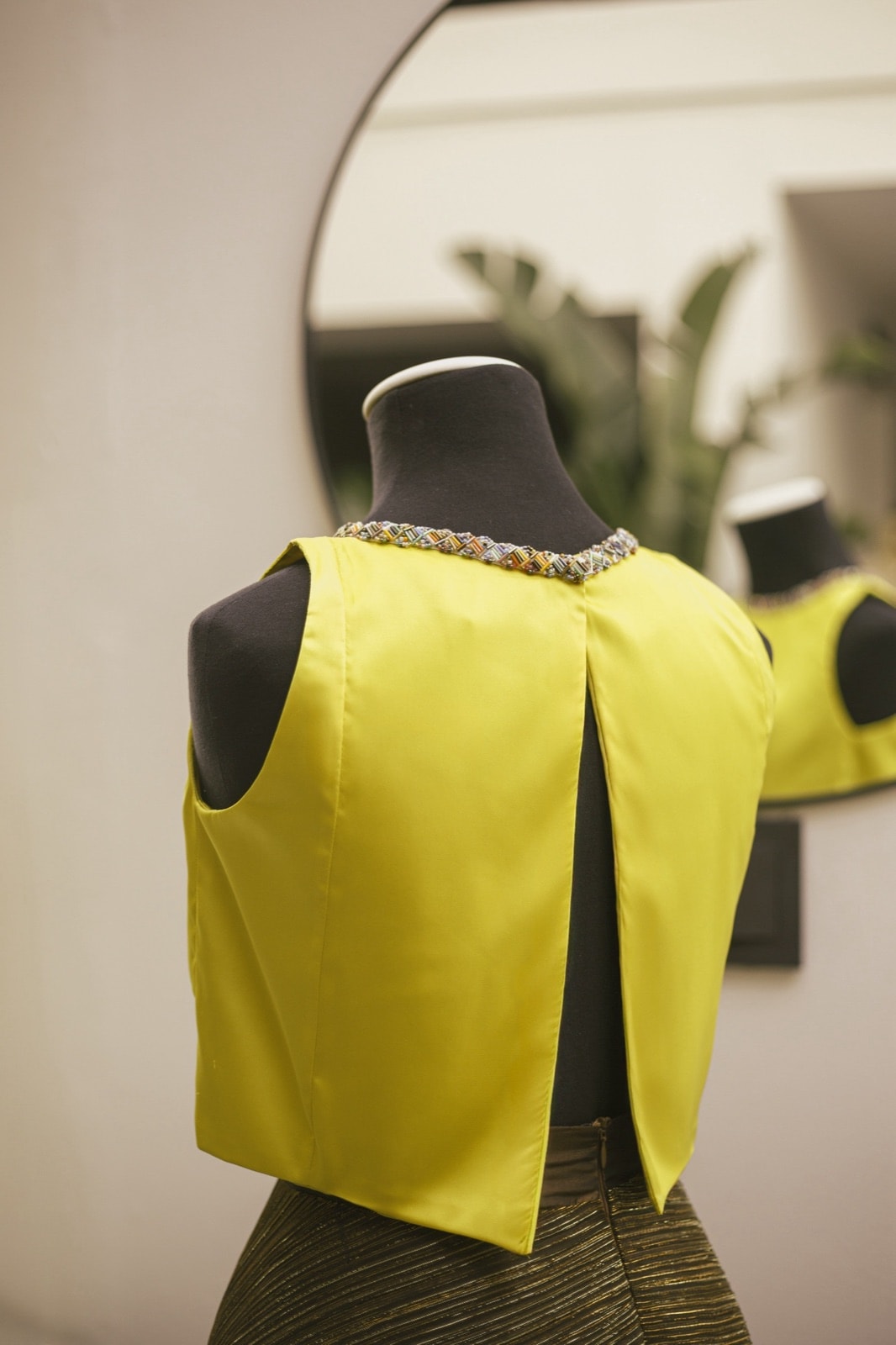 Croptop amarillo con cinta multicolor, vista de espalda sobre busto, con la abertura central en la zona baja.
