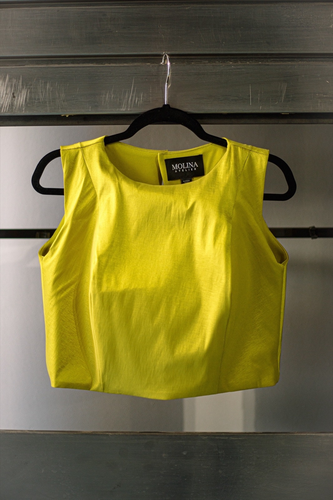 Croptop de tafetán color lima de Atelier Molina, colgado en percha, vista frontal con la etiqueta de la marca visible.