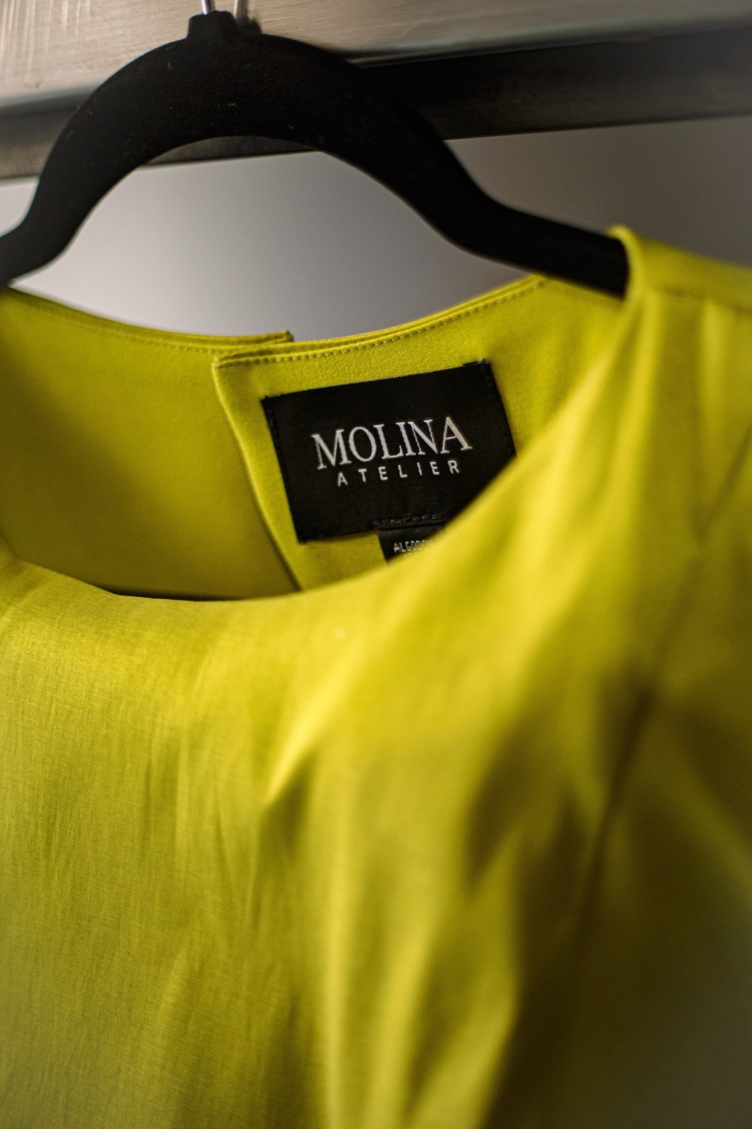 Detalle de la etiqueta Molina Atelier en el cuello del croptop de tafetán color lima, colgado en percha.