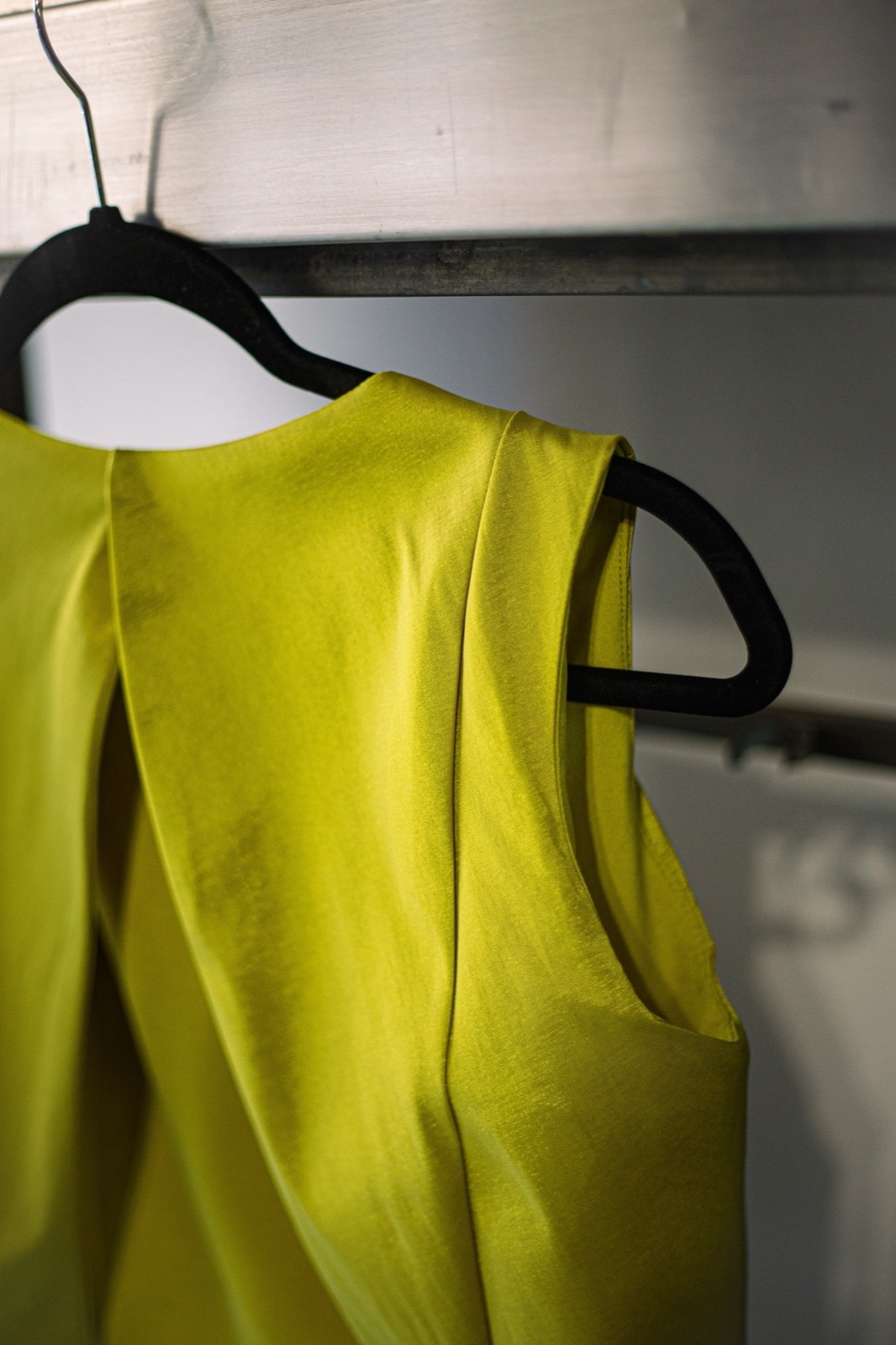 Detalle de la sisa y la costura central del croptop de tafetán color lima de Atelier Molina, colgado en percha.