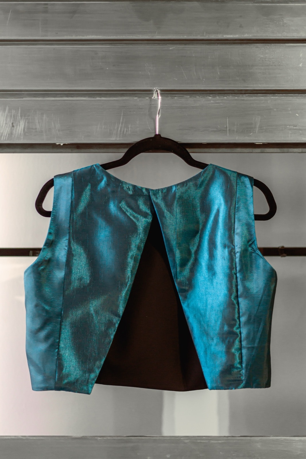 Croptop de tafetán petróleo de Atelier Molina en percha, vista de espalda con abertura triangular en el centro.