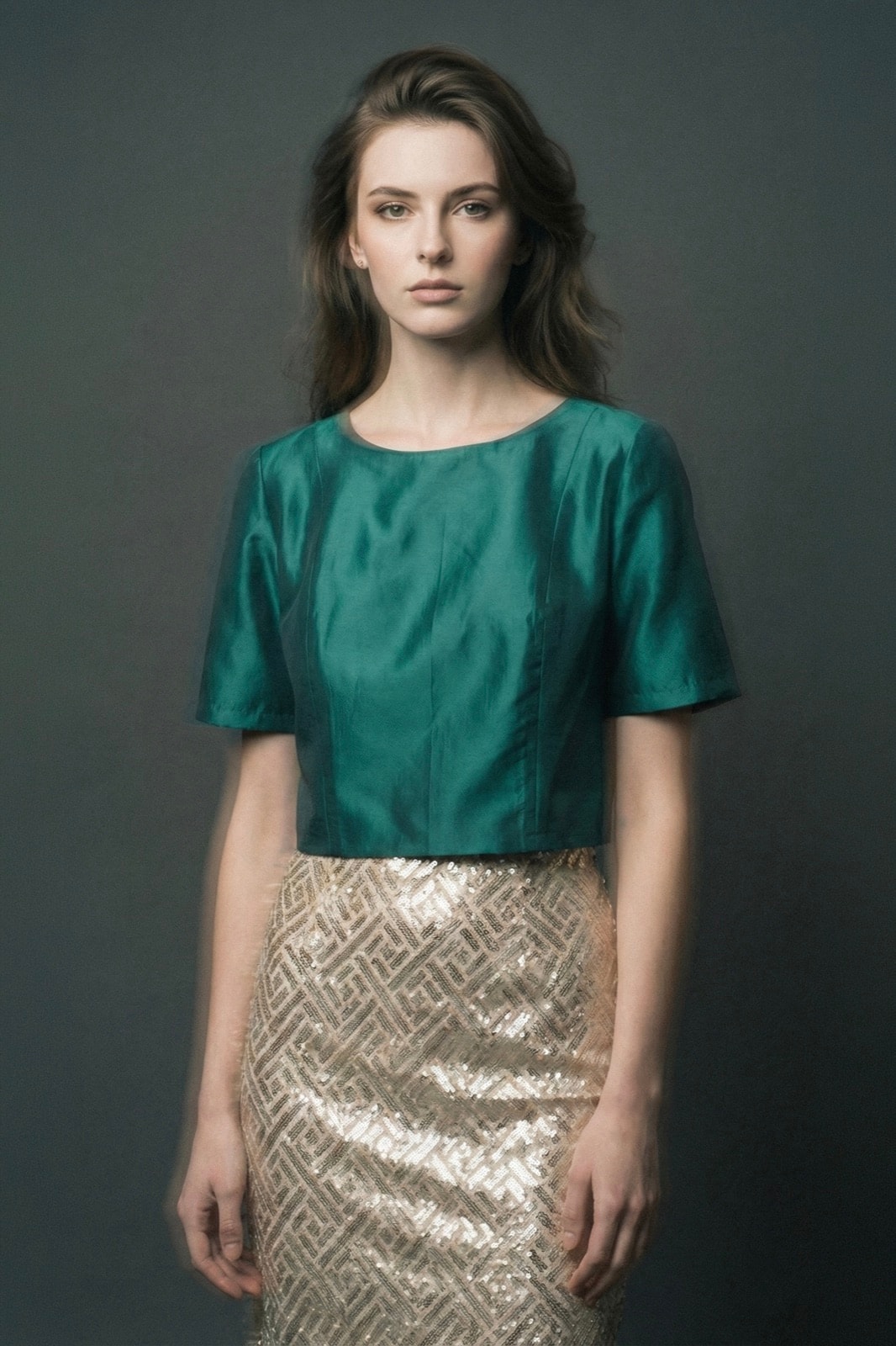 Croptop de tafetán verde petróleo con mangas de Atelier Molina, vista frontal sobre modelo con falda dorada, fondo gris de estudio.