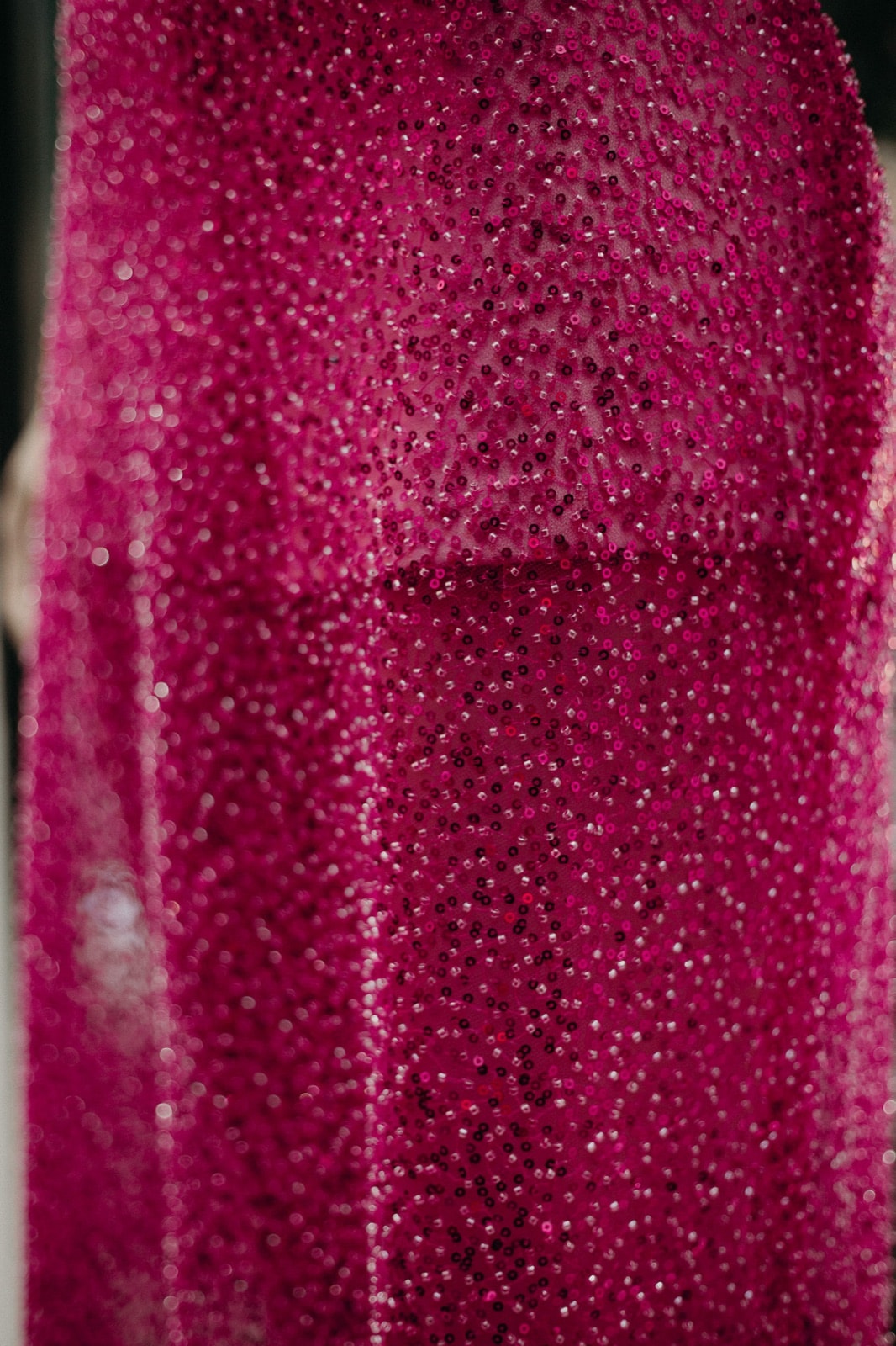 Primer plano extremo del bordado de canutillos y lentejuelas fucsia, mostrando la densidad y el brillo de la pedrería sobre la malla.