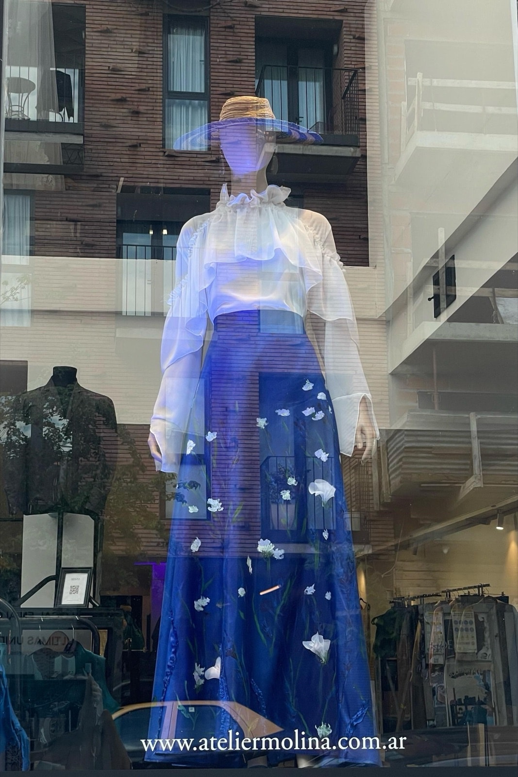 Falda de tafetán azul con jardín pintado y bordado en la vidriera del atelier, con el reflejo de los balcones de Buenos Aires.