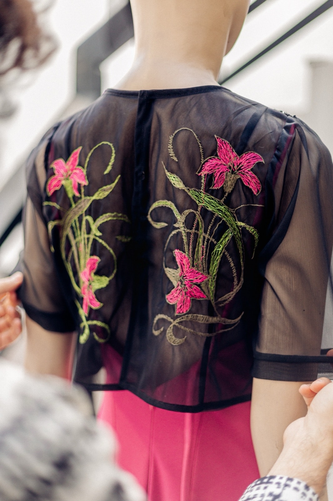 Espalda del croptop Garden Night sobre maniquí, con dos ramas de flores bordadas y las mangas cortas de tul negro.