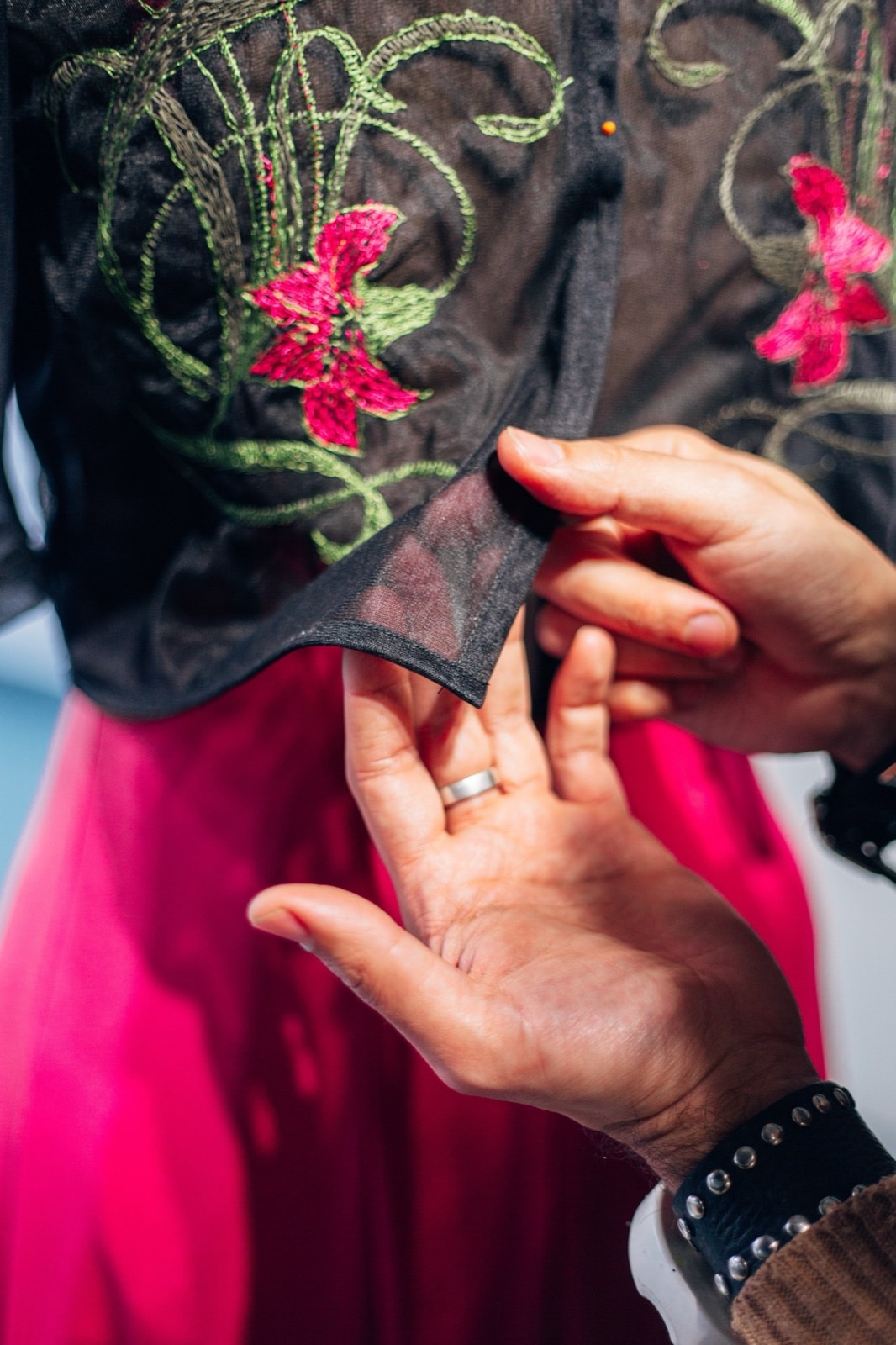 Detalle del ruedo del croptop Garden Night durante el fitting, con manos ajustando la tela sobre la falda fucsia.