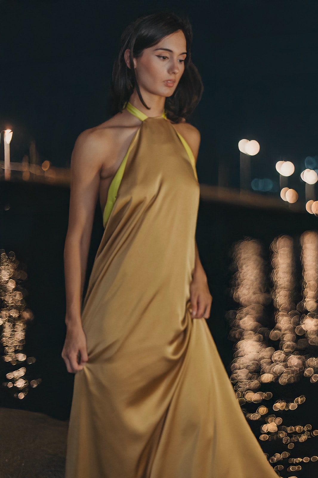 Golden Lime Dress de crepe satén dorado, vista frontal sobre modelo de noche con luces urbanas de fondo.