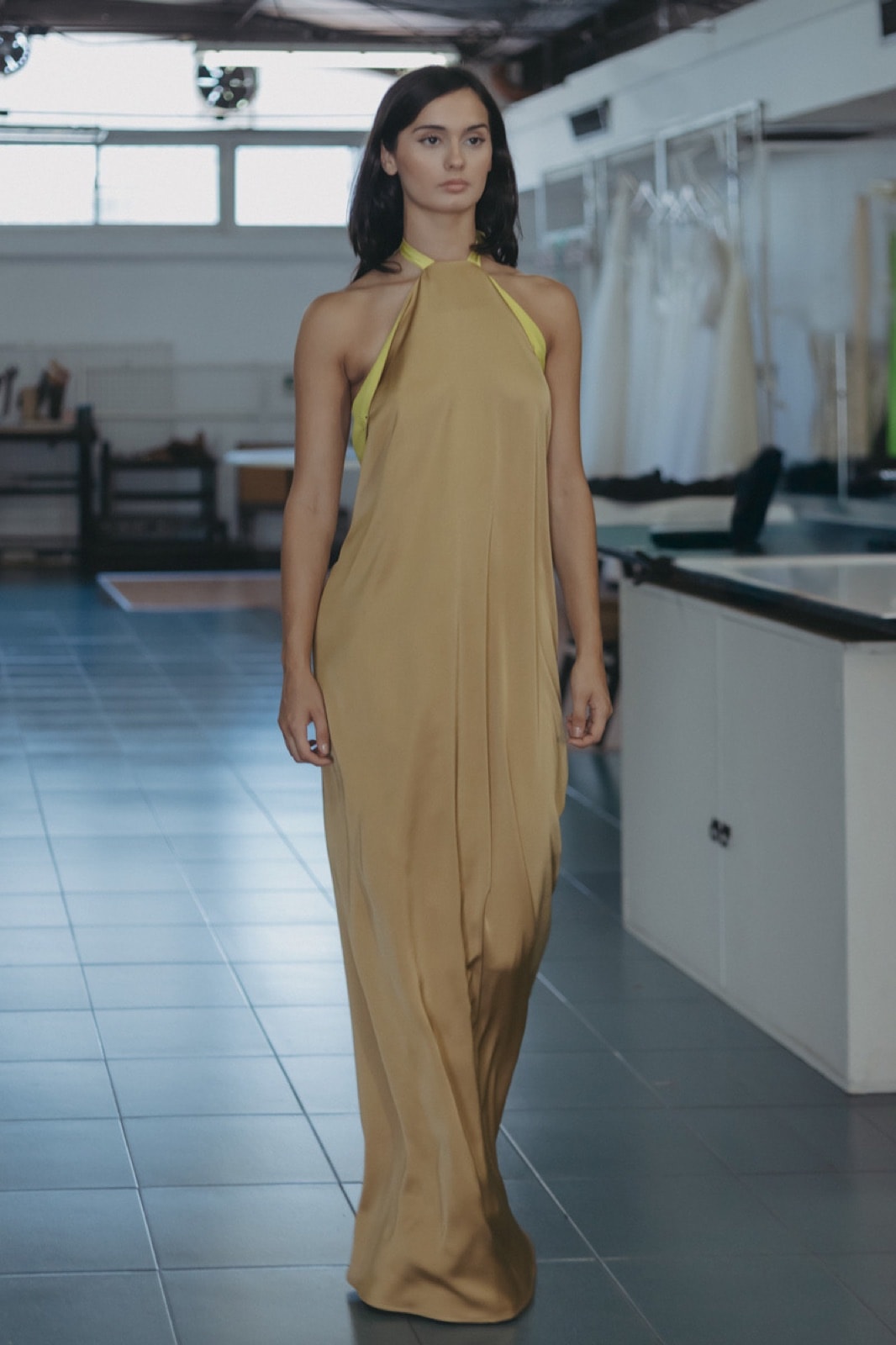 Golden Lime Dress de crepe satén dorado, vista frontal completa sobre modelo caminando en el atelier.