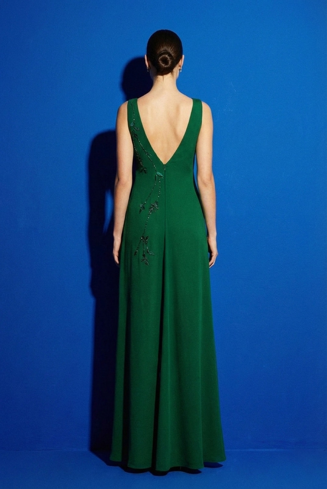 Vestido largo verde con espalda en V profunda, bordado de ramas y hojas de hilo de seda descendiendo desde el hombro, vista trasera.