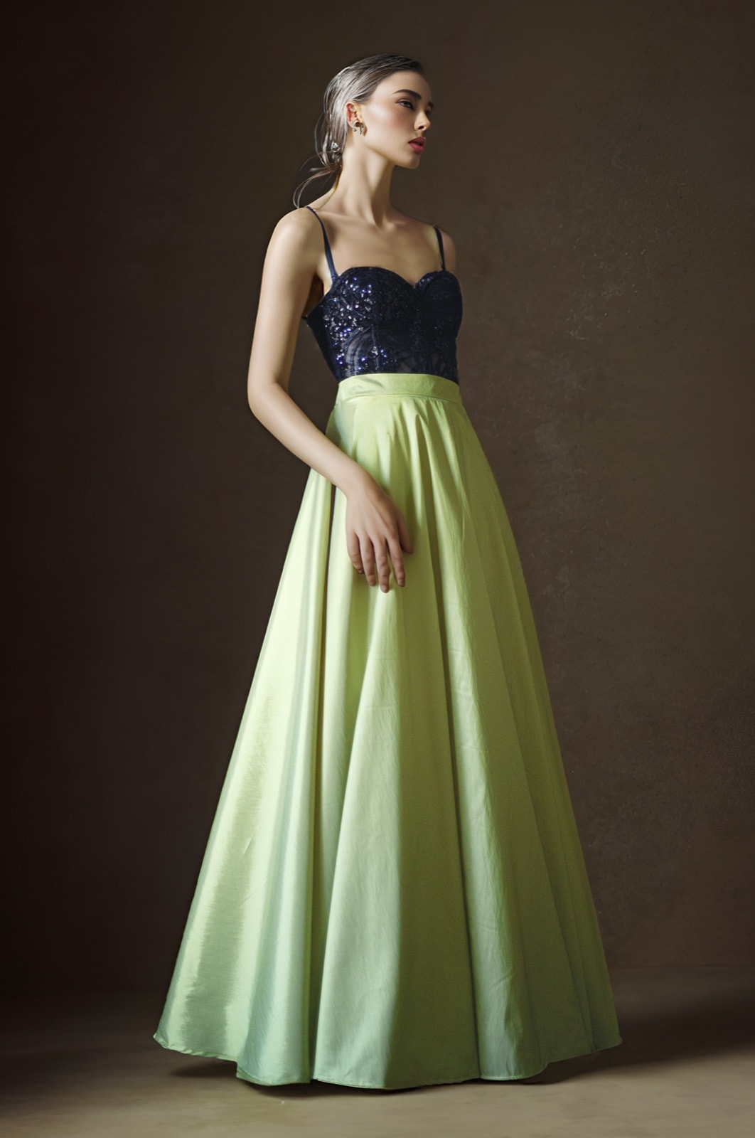 Maxi-falda de tafetán de seda color verde lima de Atelier Molina, combinada con top azul marino con brillos, fondo marrón oscuro de estudio.
