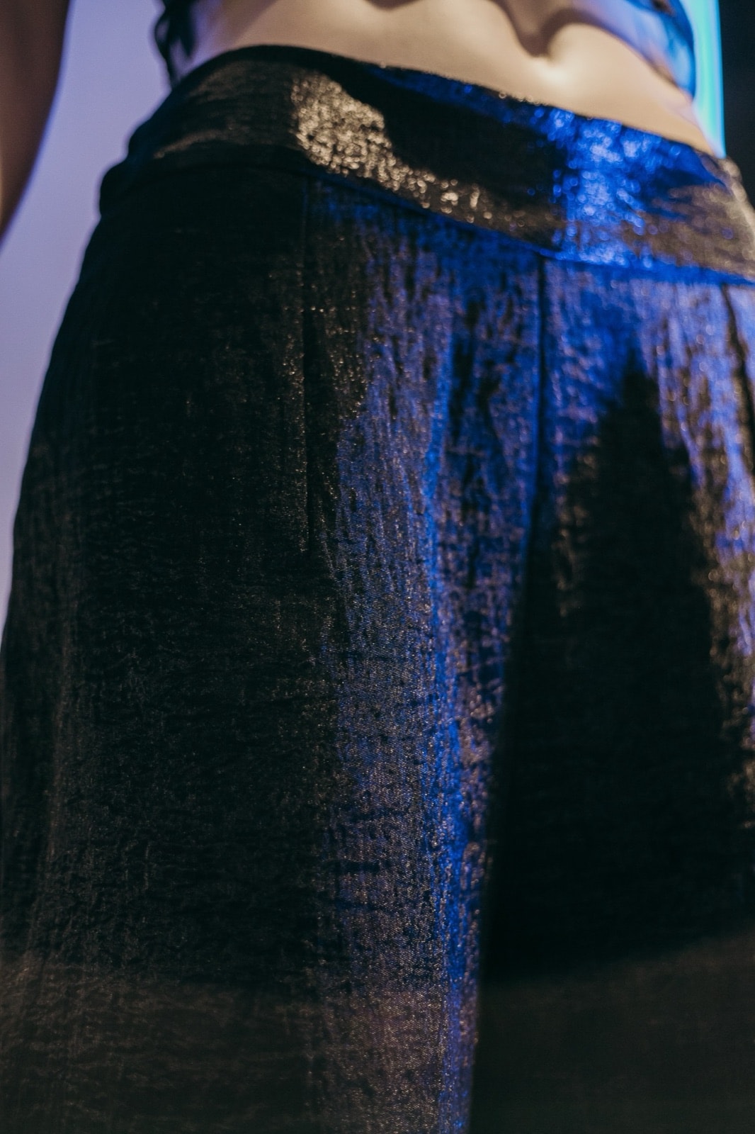 Detalle de la cintura del pantalón ancho texturado negro sobre maniquí, con el pliegue delantero y la textura arrugada.