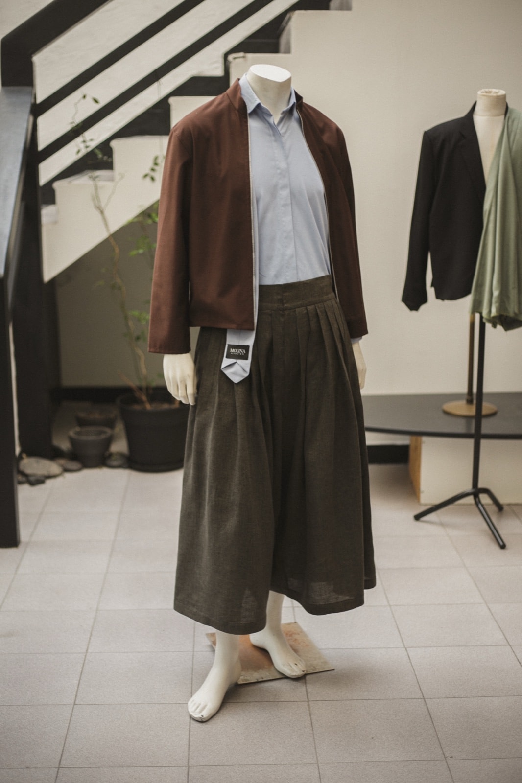 Pantalón Ritual de lino italiano verde alga sobre maniquí en el atelier, con el vuelo completo de la pierna. Atelier Molina, Buenos Aires