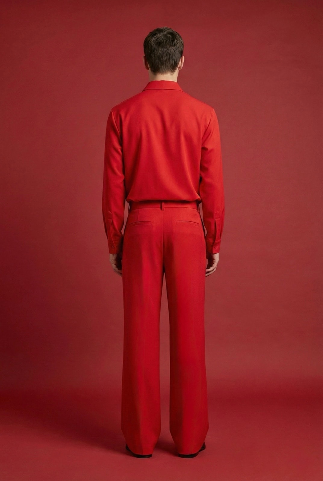 Espalda del pantalón sastrero rojo de crepe de Atelier Molina, sobre modelo con camisa a tono, fondo rojo.