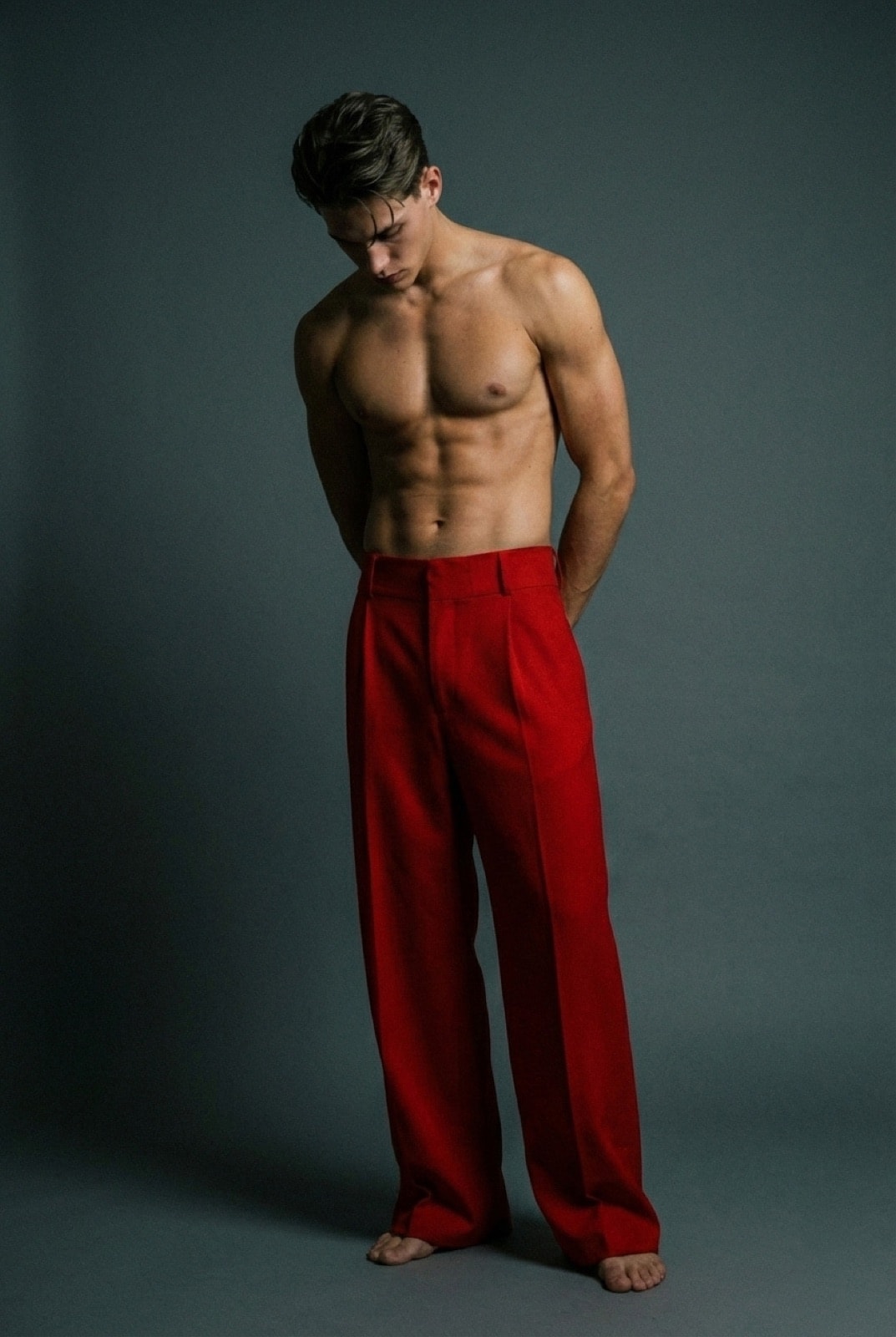 Pantalón sastrero rojo de crepe de Atelier Molina, vista frontal sobre modelo con torso descubierto, fondo gris oscuro.