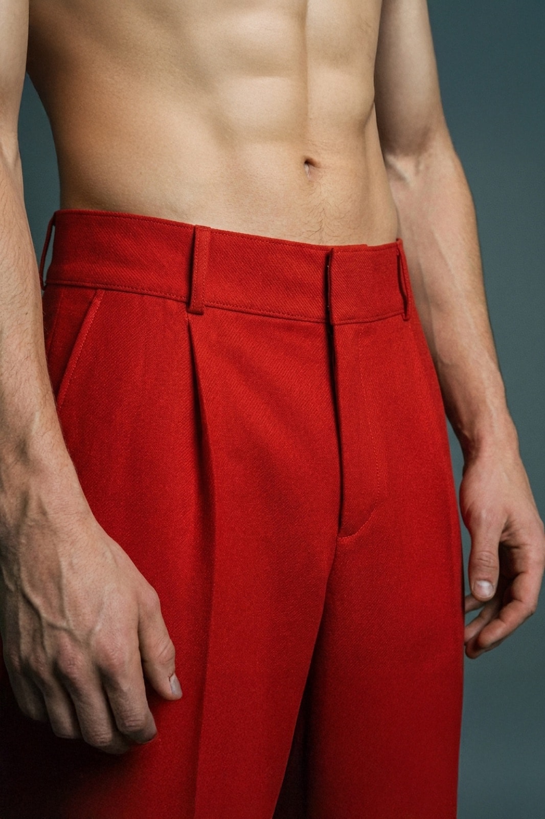 Detalle de la pretina y el cierre frontal del pantalón sastrero rojo de crepe de Atelier Molina, primer plano sobre modelo.