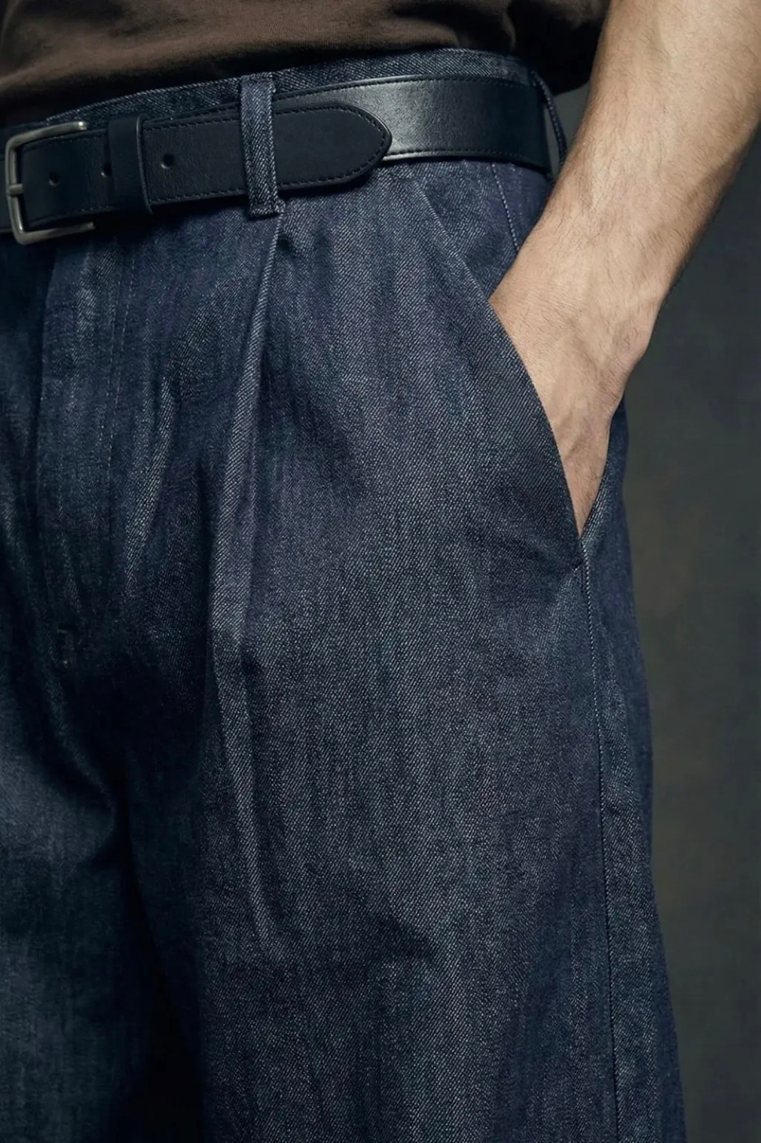 Detalle de la pretina y el bolsillo delantero del Pantalón Sastrero Molina en denim raw índigo, con la mano del modelo dentro.