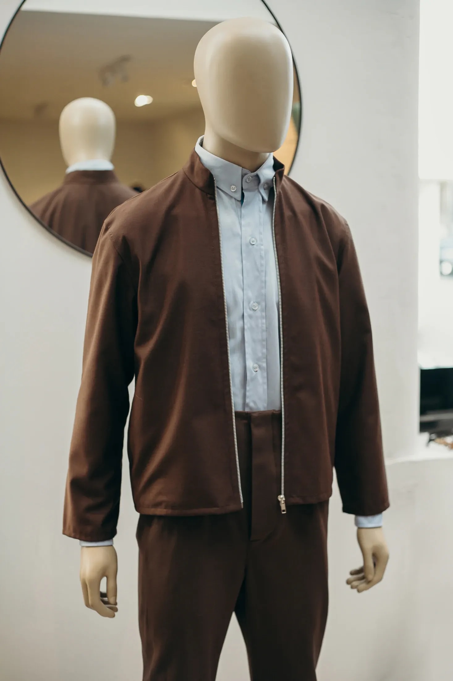 Pantalón sastrero tiro alto chocolate en tencel, detalle de cintura y cierre sobre maniquí