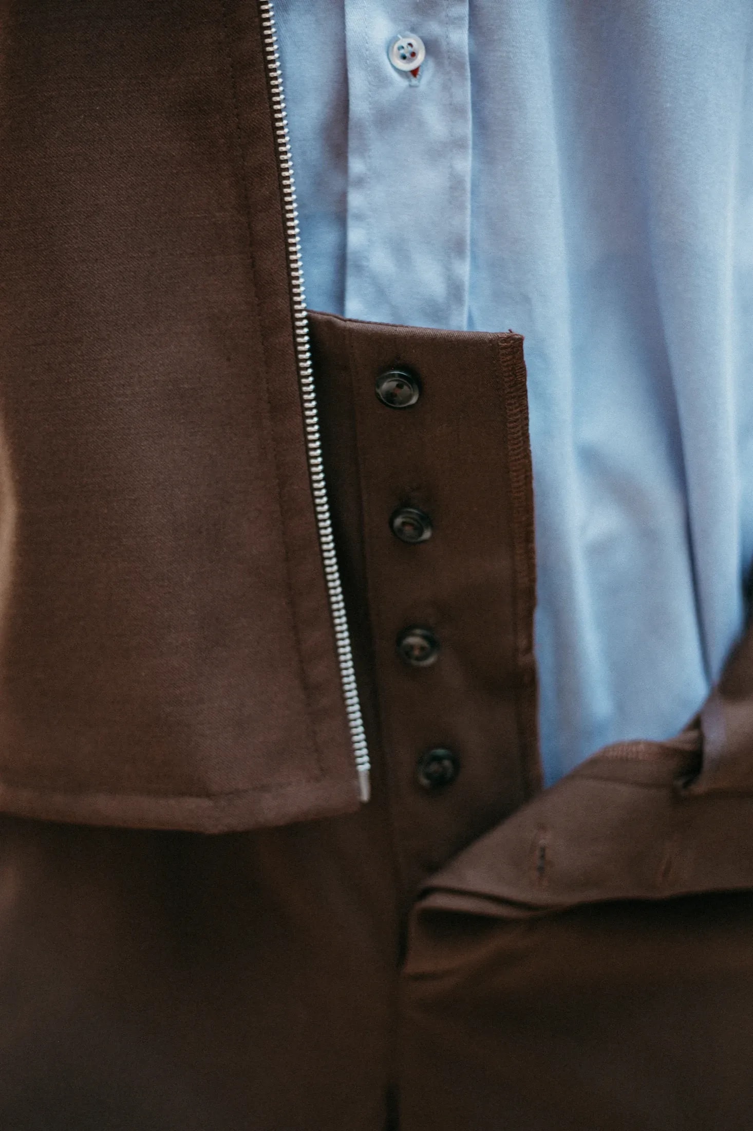Pantalón sastrero tiro alto chocolate en tencel, detalle de cierre y puño de camisa