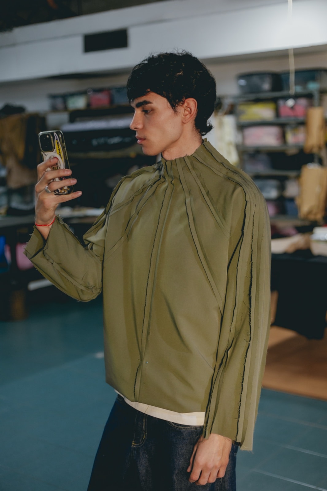 Detalle de las costuras expuestas de borde crudo y del cuello alto de la remera radial verde de Atelier Molina, Buenos Aires