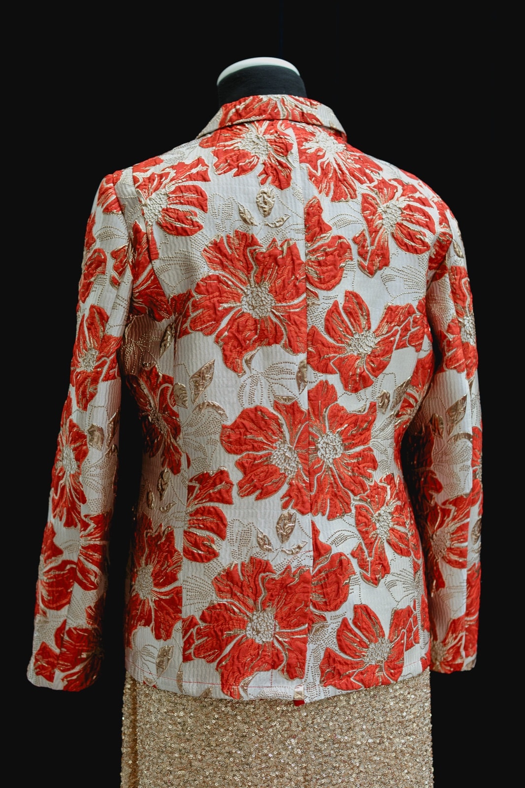 Espalda del saco de brocato con estampa floral roja y dorada de Atelier Molina, sobre maniquí.