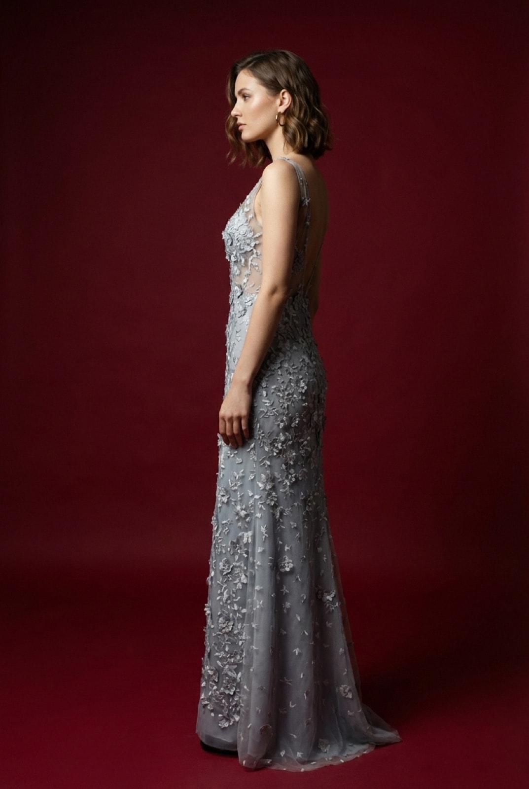 Vestido largo de tul plateado bordado con flores de Atelier Molina, vista de perfil sobre modelo, mostrando la caída de la falda hasta el piso.