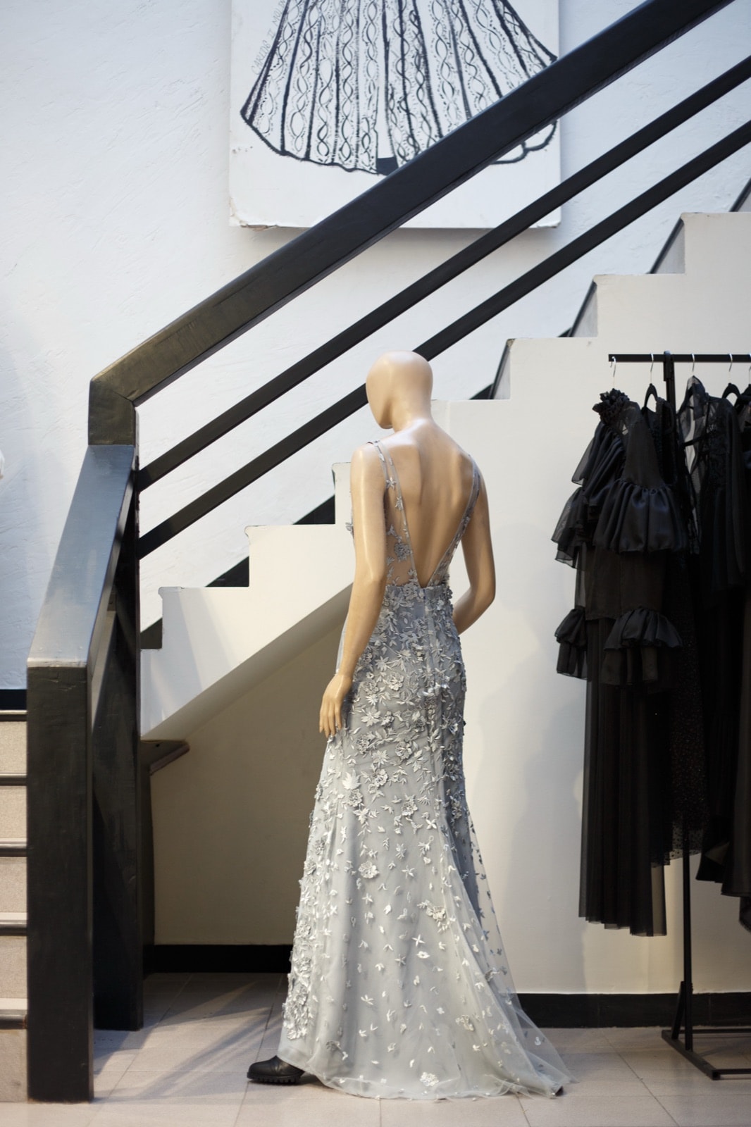 Vestido de tul plateado bordado con flores de Atelier Molina sobre maniquí, vista de espalda junto a una escalera del atelier.