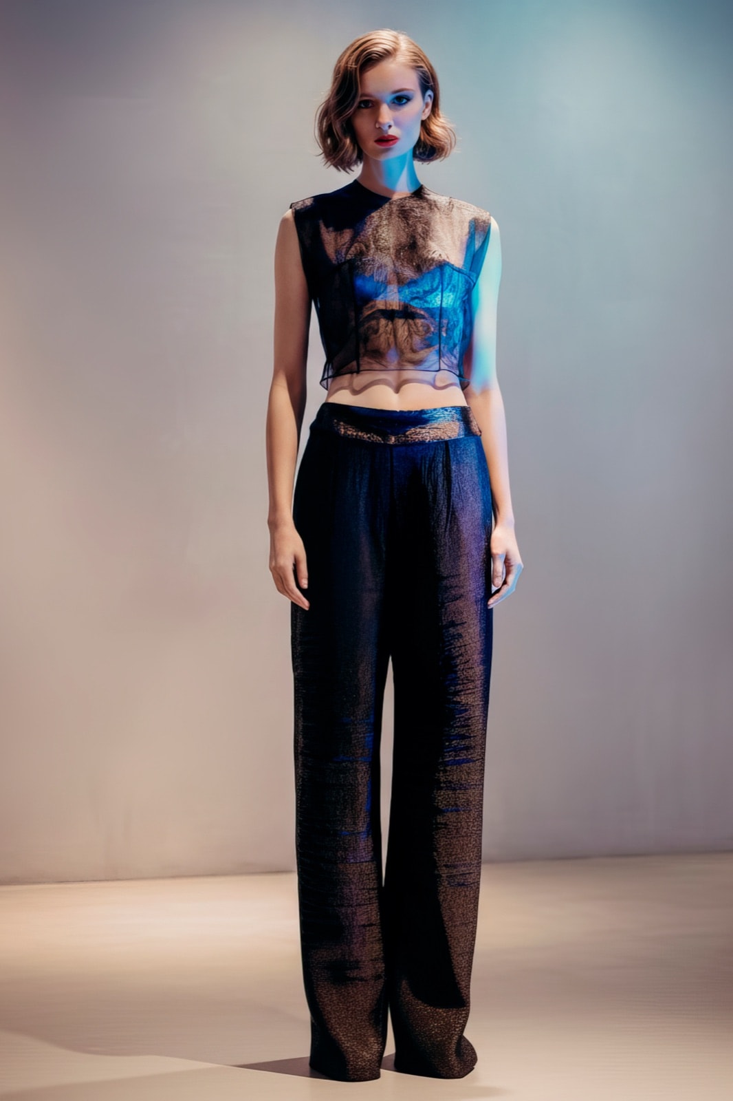 Top Tattoo en tul negro transparente combinado con pantalón ancho a juego, vista delantera completa bajo luz azulada de estudio.