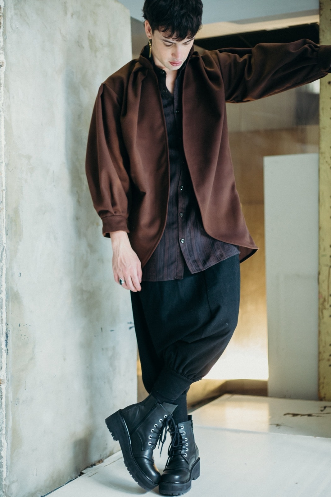 Saco tulip chocolate de Atelier Molina sobre modelo en movimiento, con un brazo extendido y botas negras de cordones.